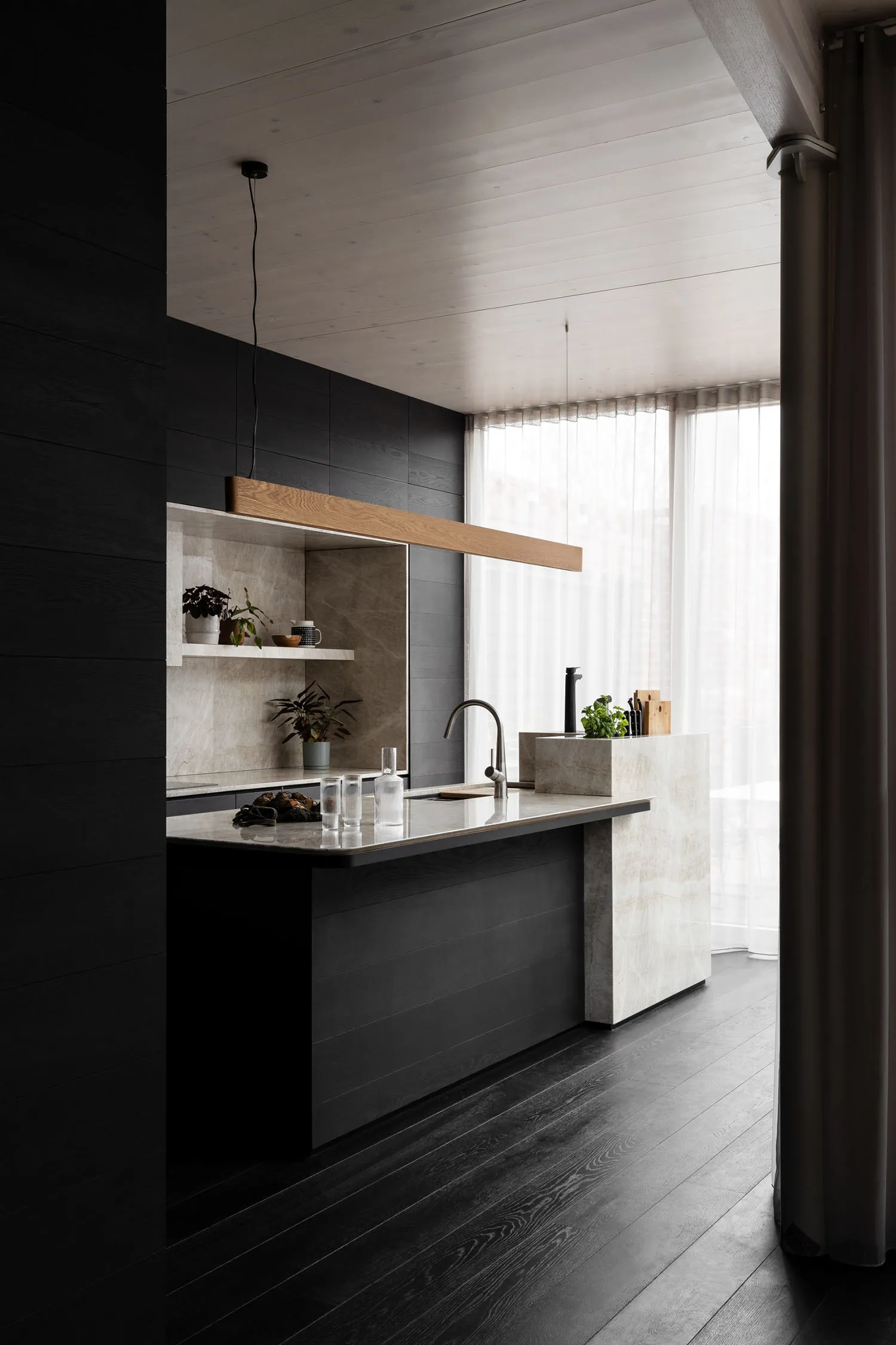 Modern kitchen with marble countertops and black wooden floors.