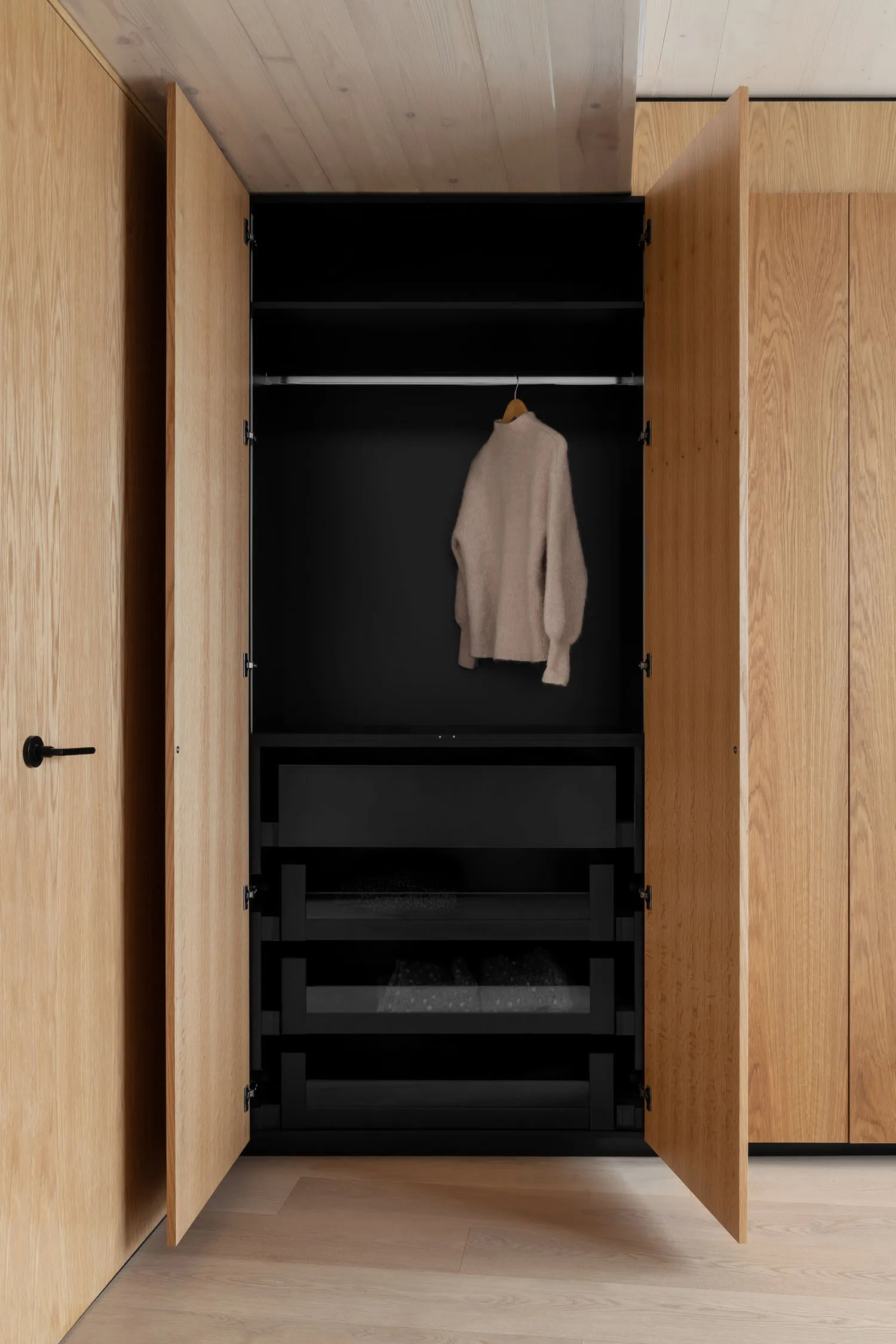 A modern wardrobe with wooden doors and black interior, showcasing a minimalist design.