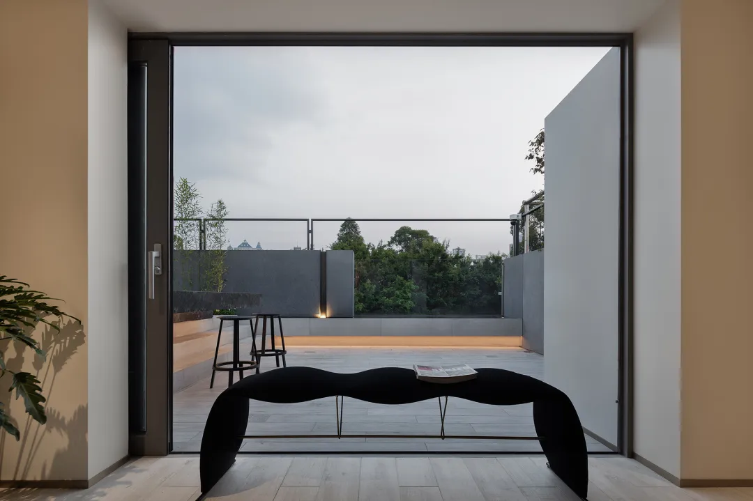 Modern interior space with sleek black bench, glass walls, and concrete flooring.