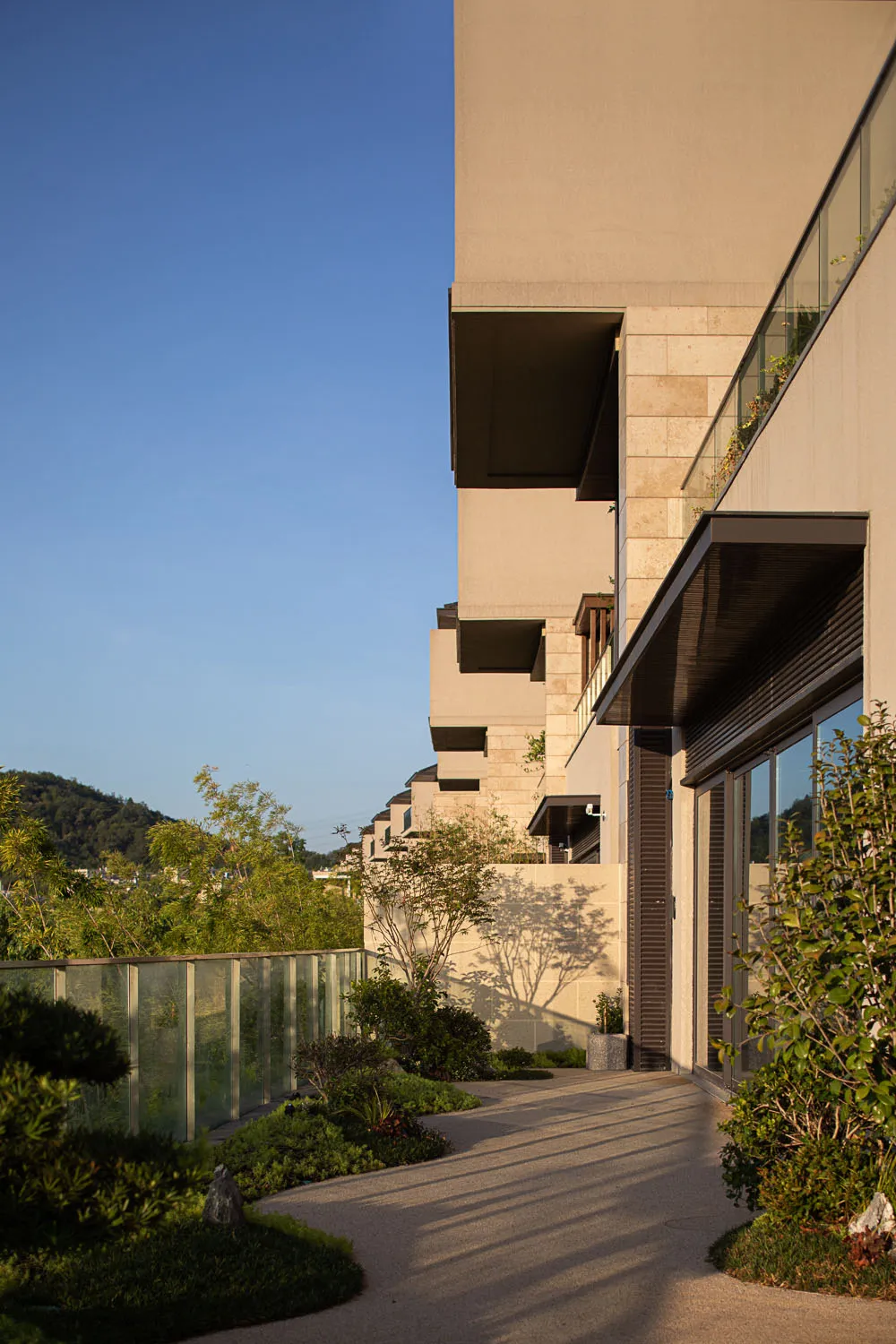 A modern residential building with concrete exterior walls and extensive greenery.