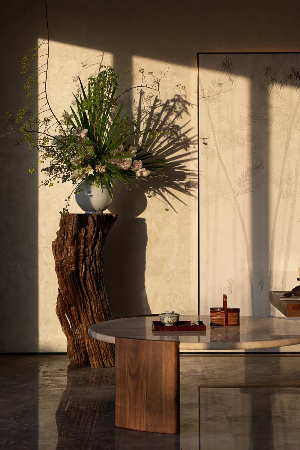 Marble coffee table and wooden stool in a living room with natural light streaming in through the windows.