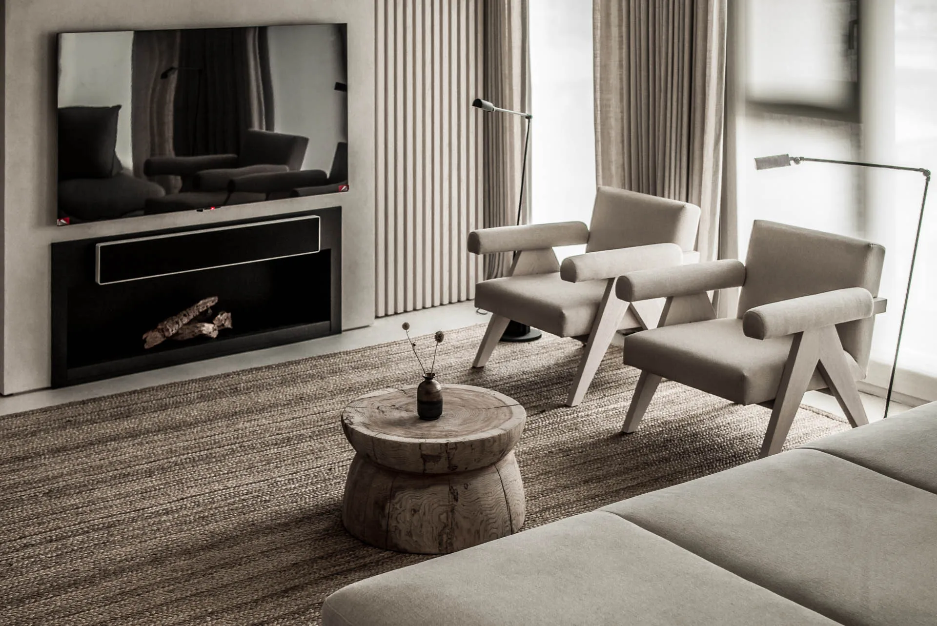 A modern minimalist living room with cushioned furniture, a wooden table, and a flat-screen TV mounted on the wall.