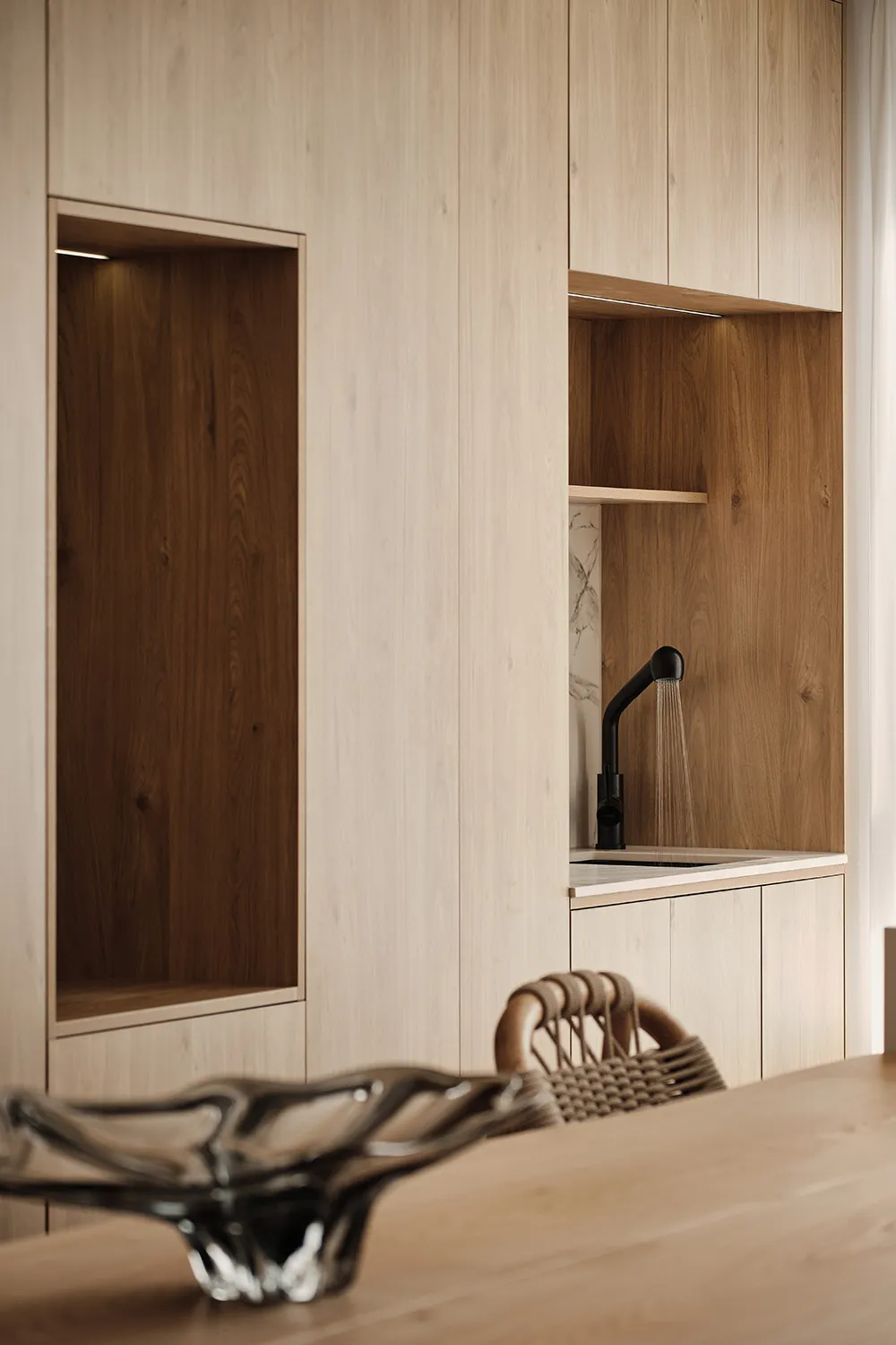 Modern minimalist kitchen with wood cabinets and a sleek sink.