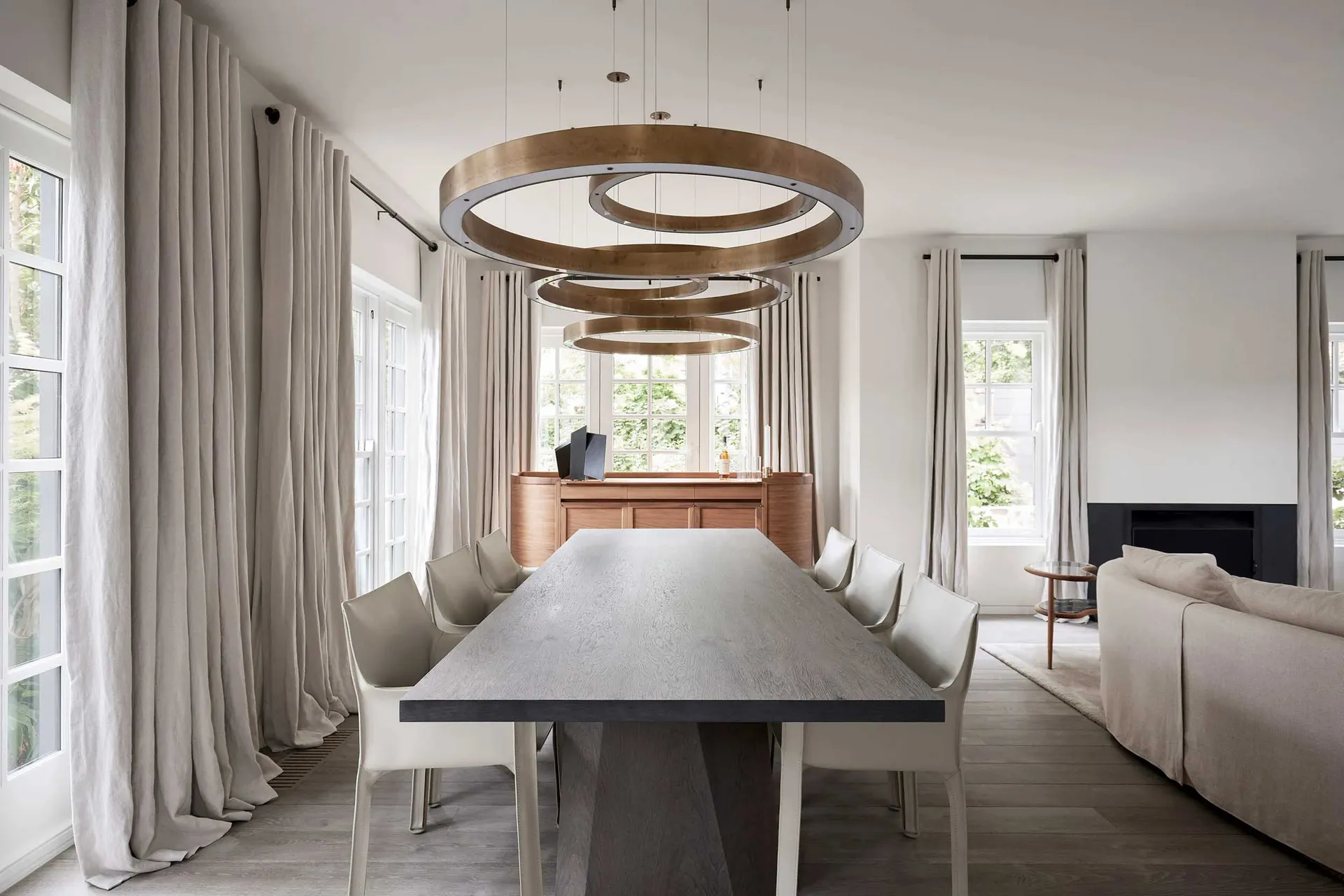 Modern dining room featuring natural wood dining table and chairs, with large windows, pendant lighting, and clean lines.