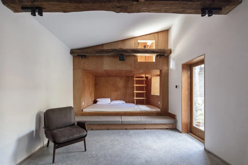 A modern minimalist bedroom with wood features and a bed built into the wall.