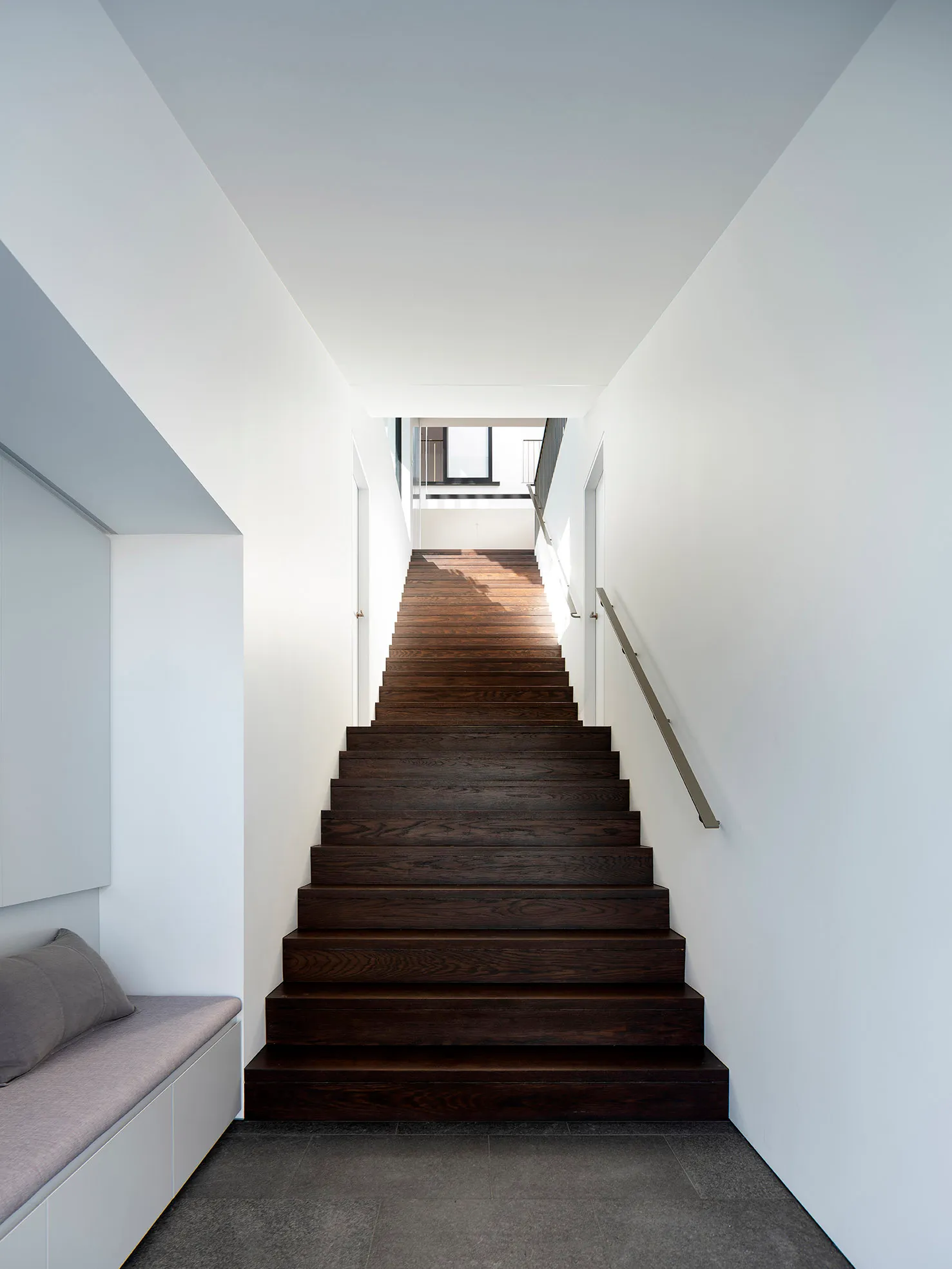 A modern staircase with dark wood treads and light-colored walls.