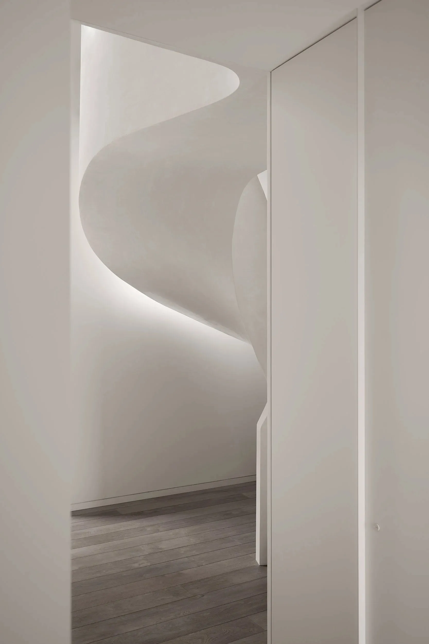 White concrete spiral staircase with minimalist design and soft lighting.