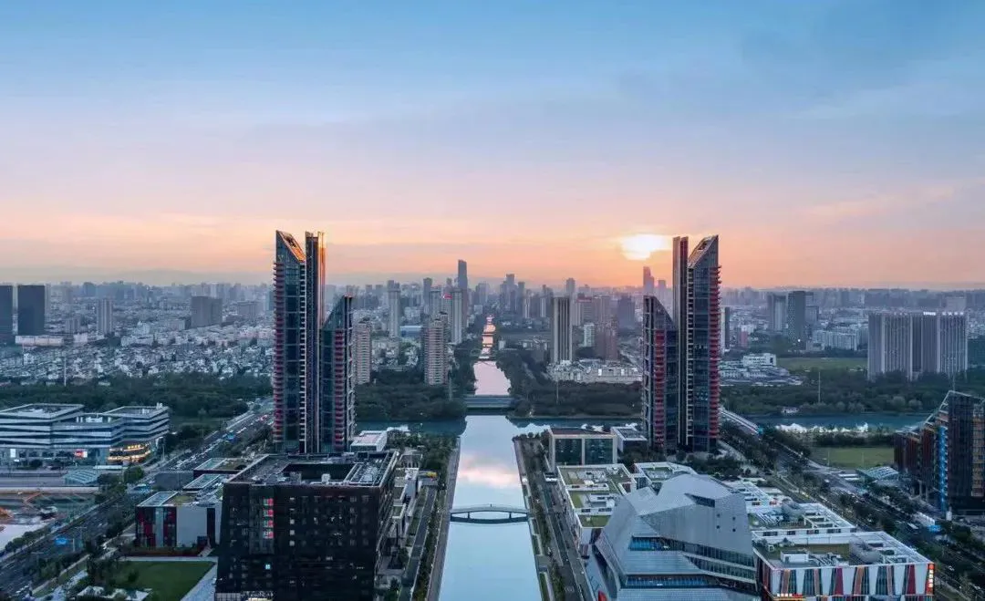Modern urban landscape featuring glass, concrete, and steel buildings at sunset.