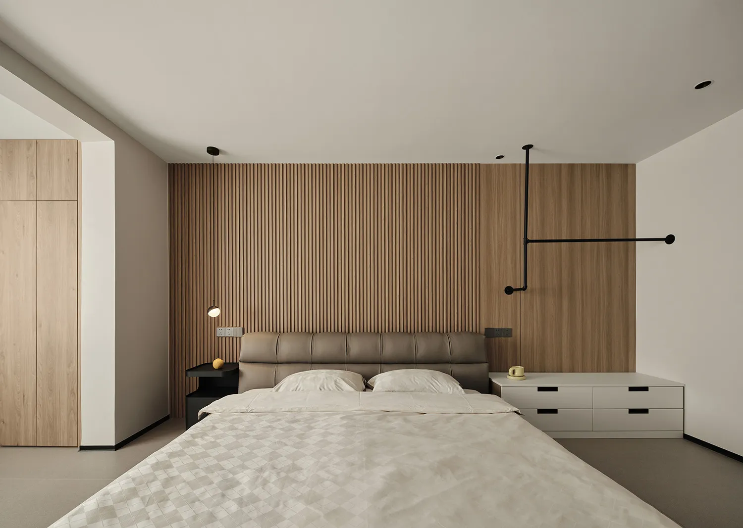 Modern minimalist bedroom with a wood paneled wall, featuring a large bed with white linens and a sleek, contemporary design.