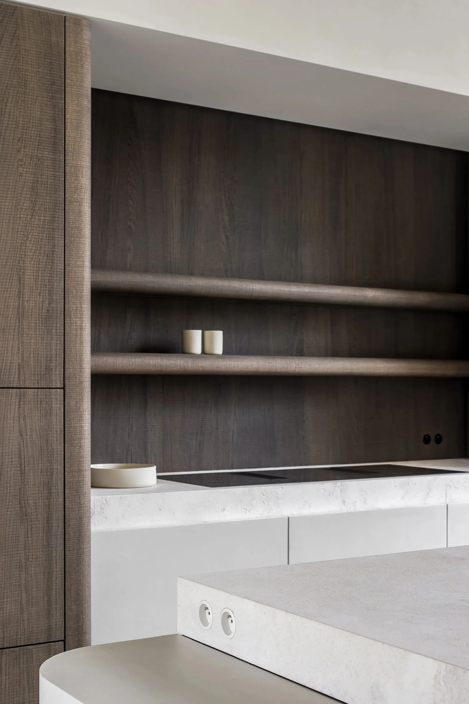 A modern minimalist kitchen with concrete and wood finishes and white shelves.