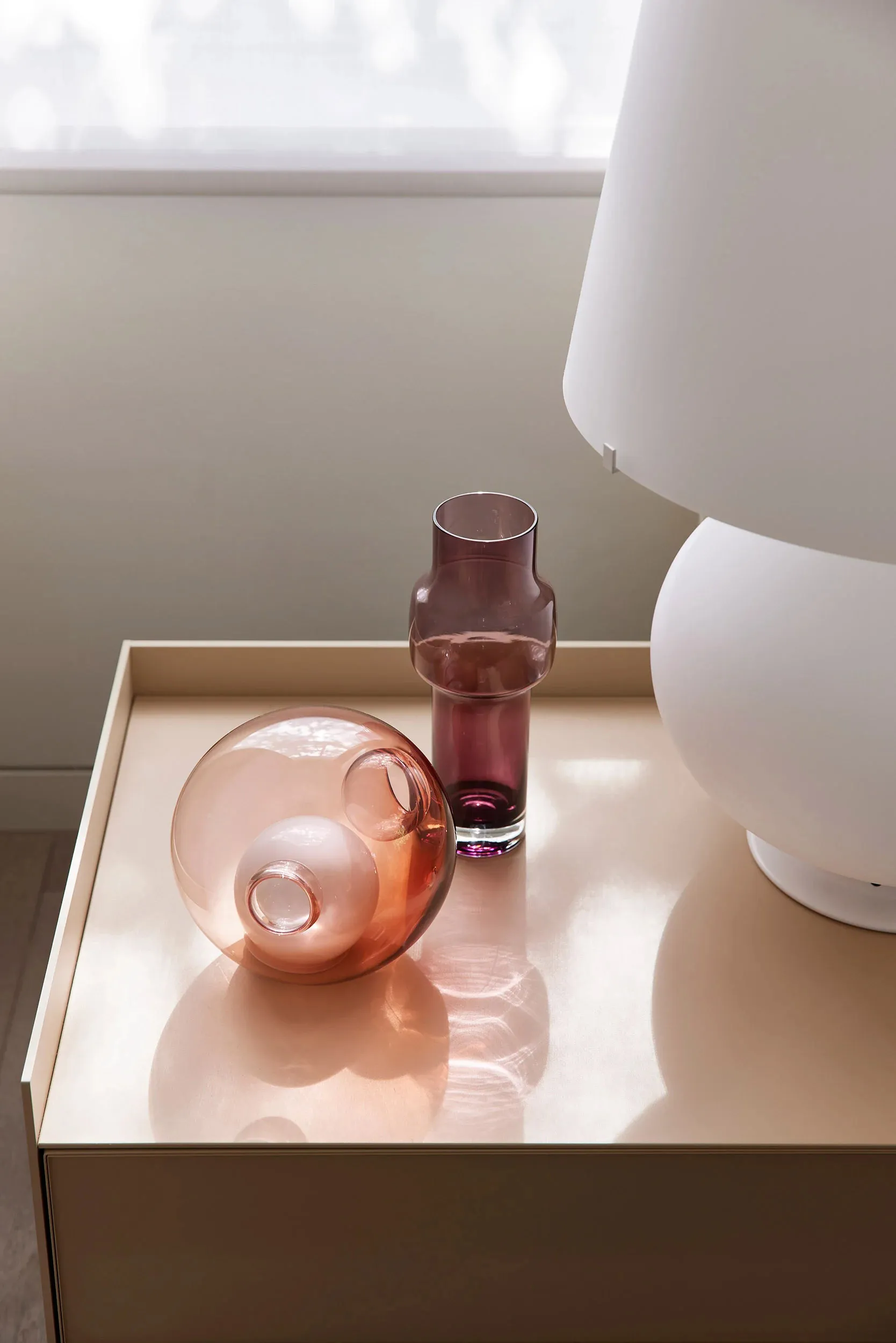 Modern side table with glass vessels and a white lamp。