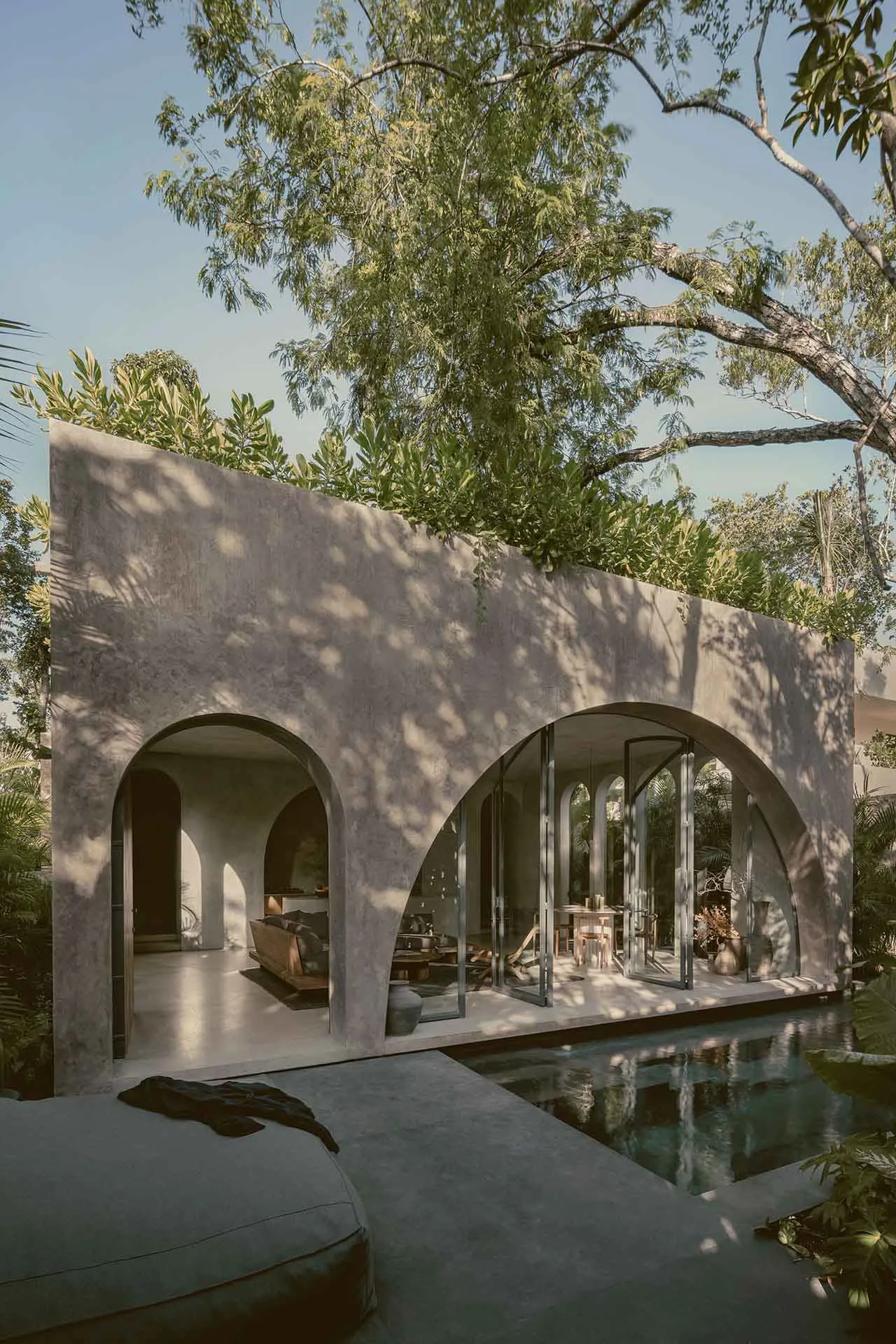 An outdoor living space with a modern design, featuring concrete walls, glass doors, and a pool.