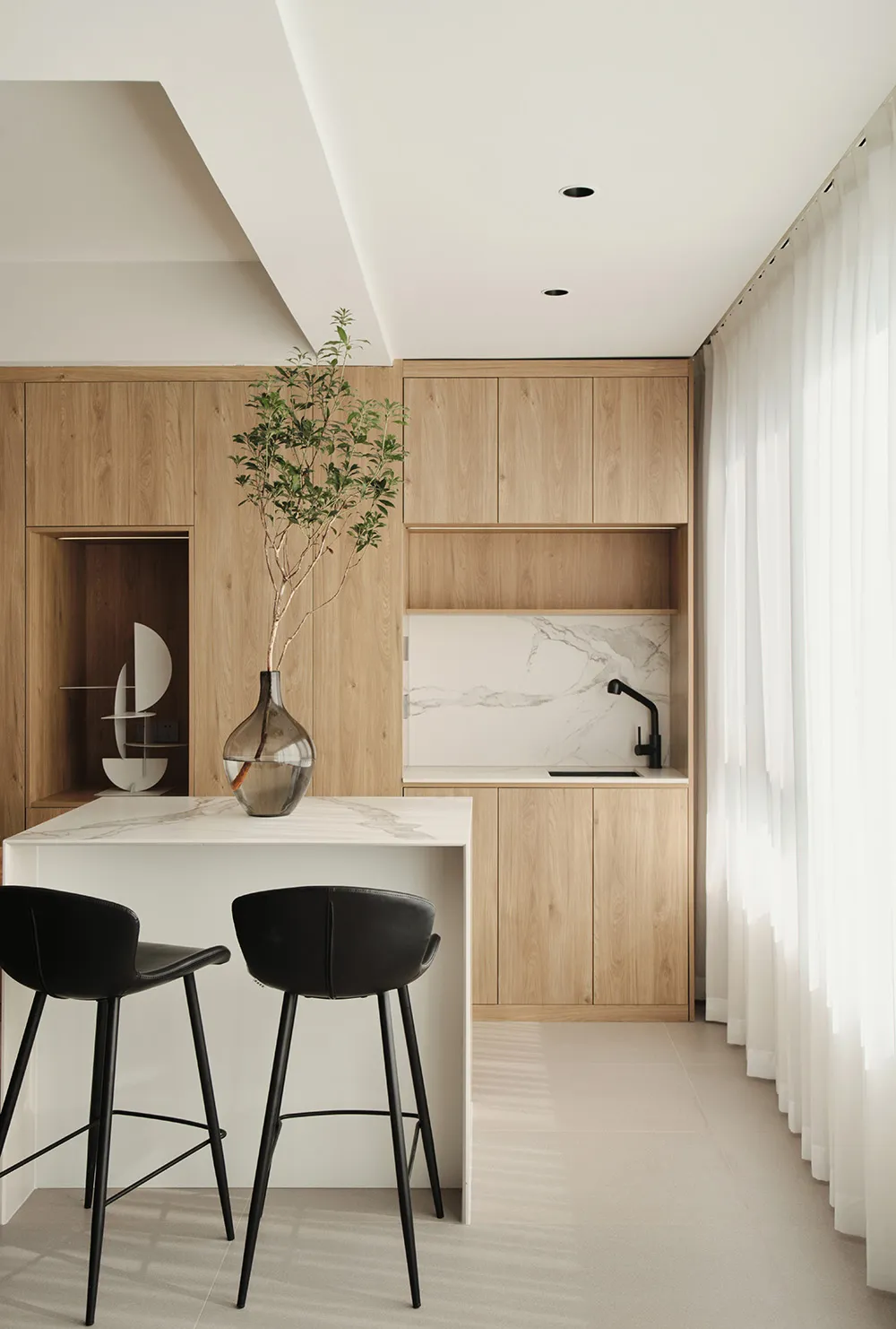 A modern minimalist kitchen featuring wood cabinetry and a marble countertop.