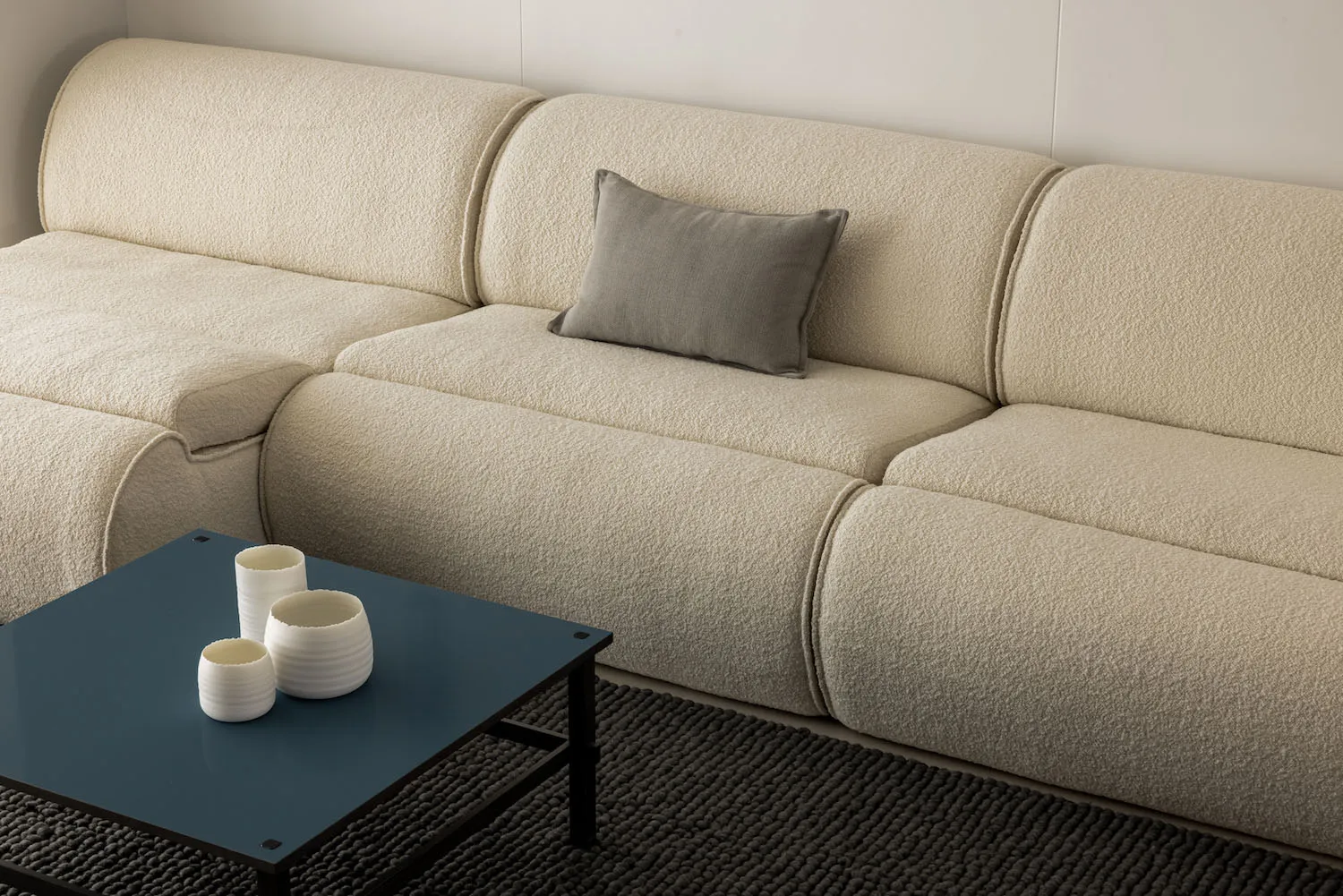 A modern sectional sofa with a textured fabric upholstery in a minimalist living room setting.