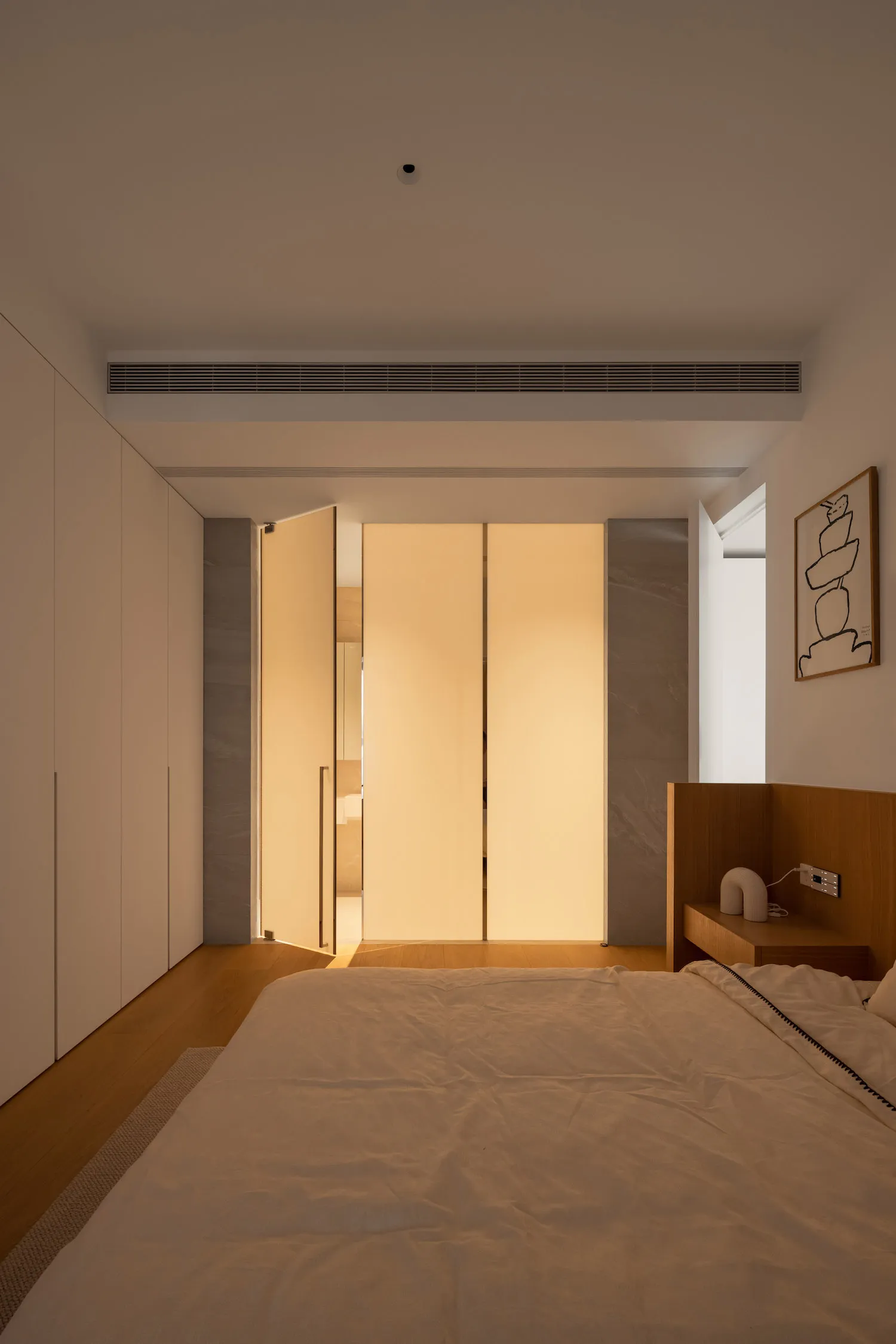 A modern minimalist bedroom with wooden flooring, marble accents, and a light-filled atmosphere.