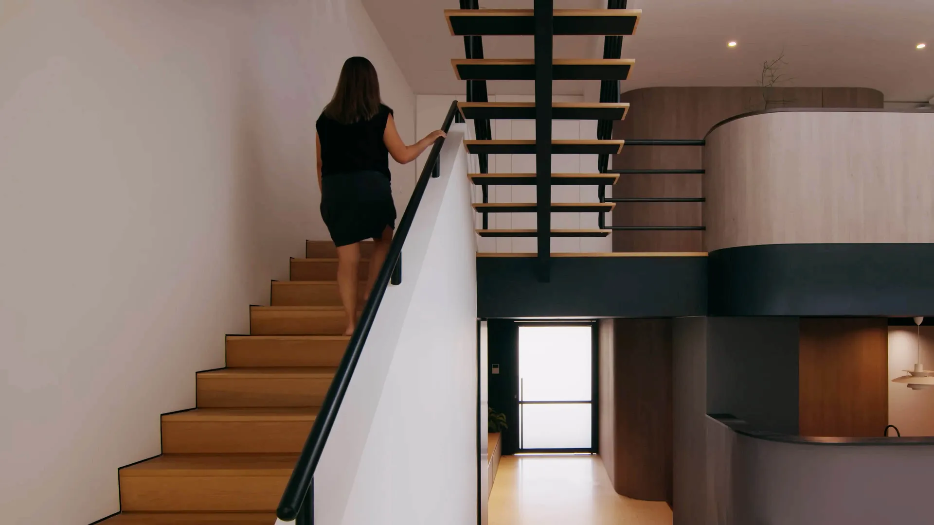 A woman descends a modern industrial staircase made of metal and wood.