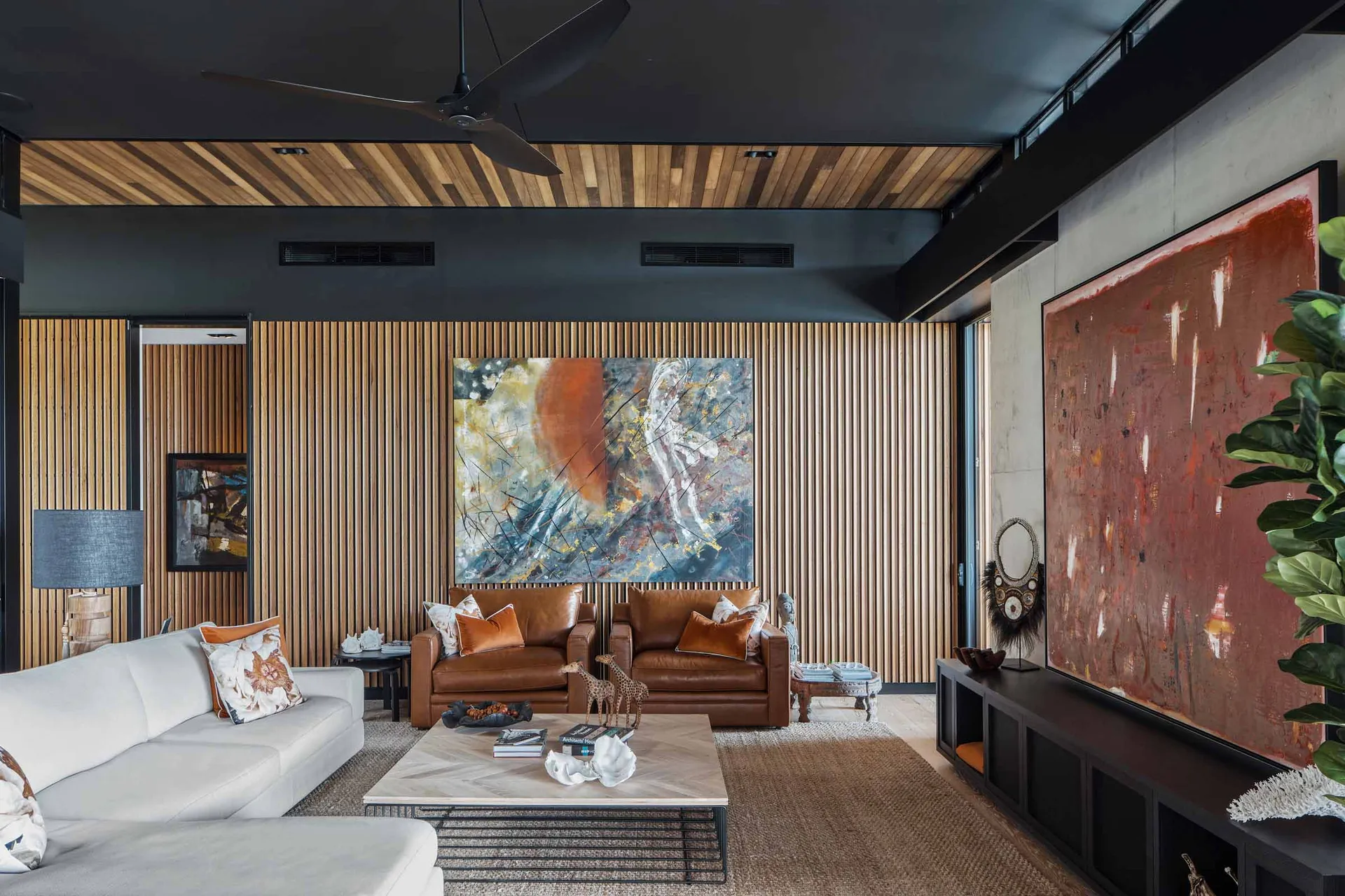 A modern living room featuring wooden walls, a metallic coffee table, and leather furniture.