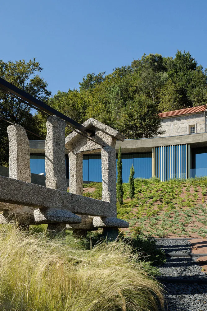 Modern, outdoor sculpture made of stone and metal with green grass in the foreground