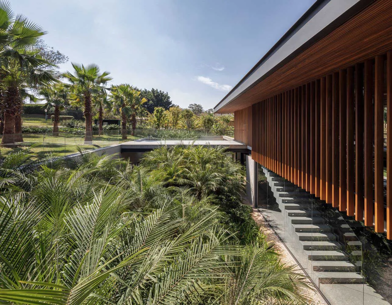 Modern residential exterior featuring a wooden exterior with large glass windows and a concrete foundation.