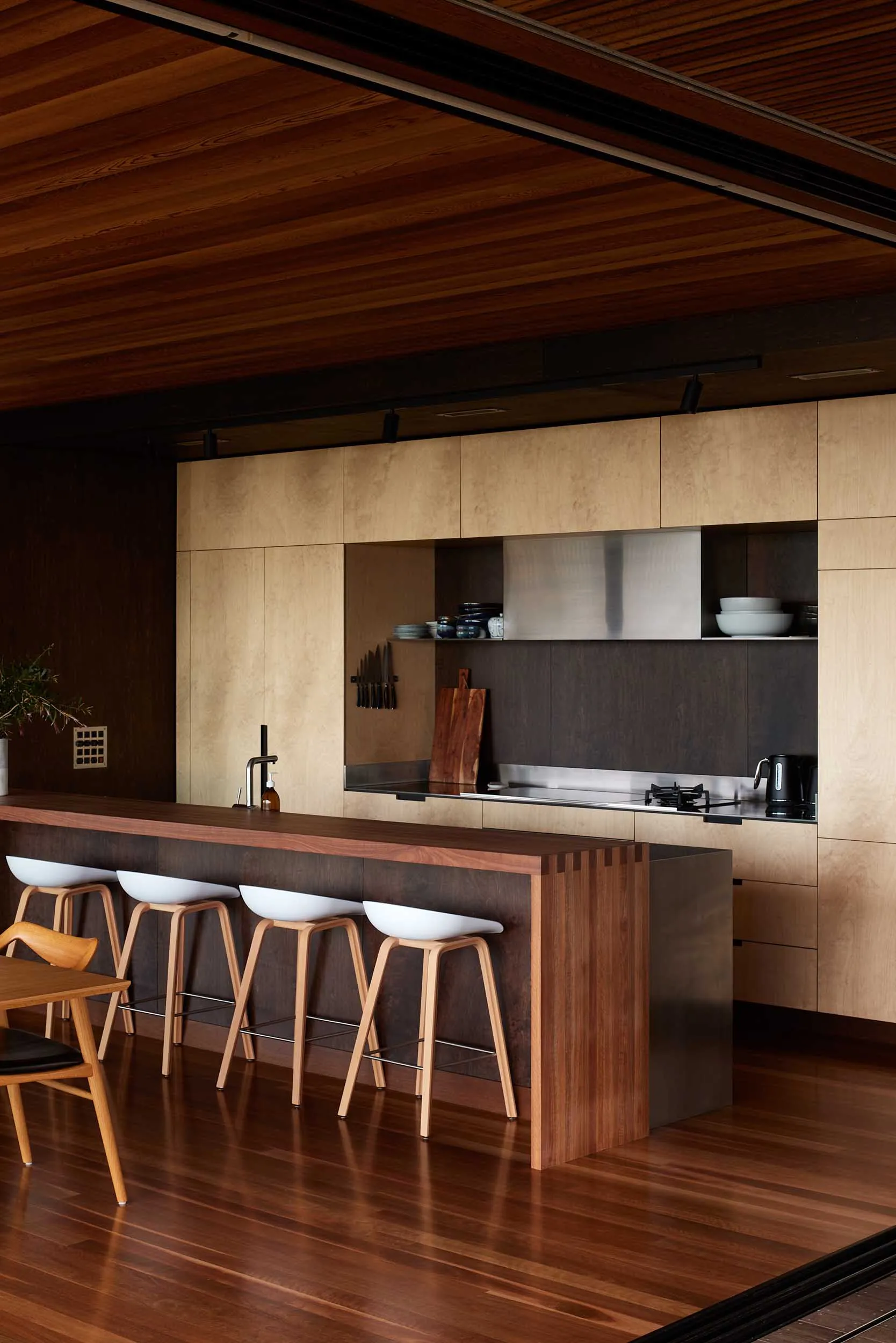 Modern minimalist kitchen with wooden surfaces, metallic accents, and ceramic tiles.