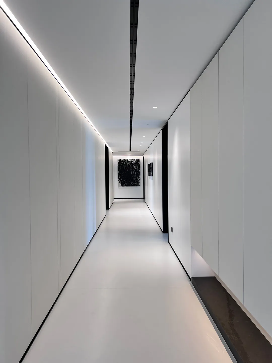 A minimalist white corridor with panels on the walls.