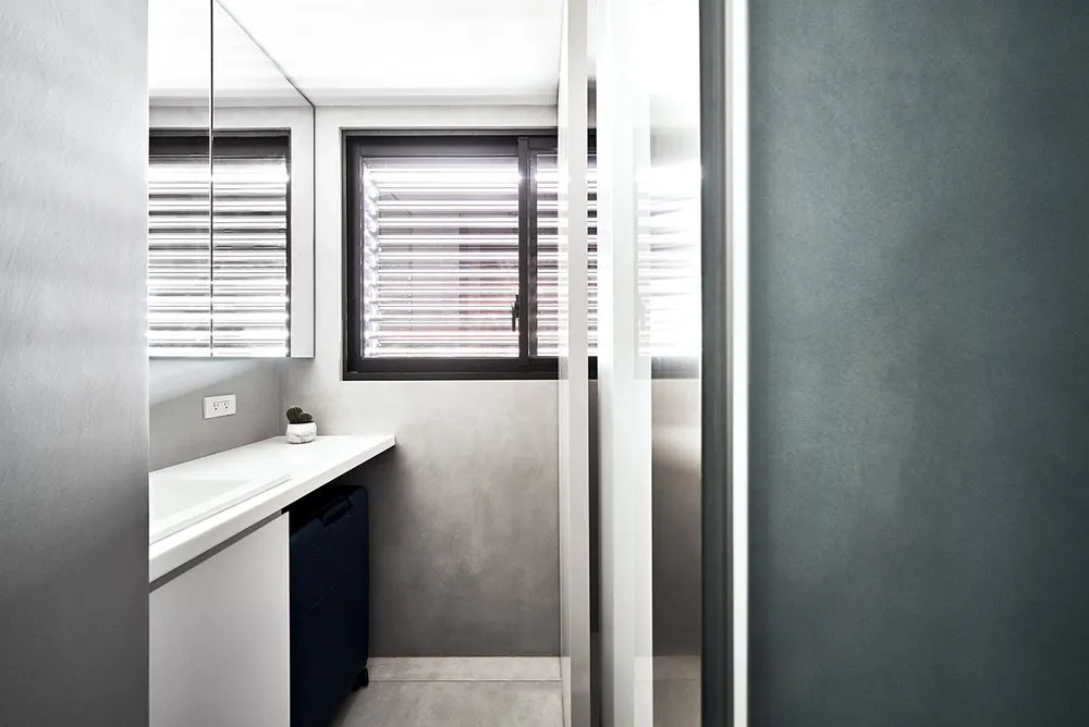 A minimalist bathroom with concrete walls and floor, featuring window blinds and modern fixtures.