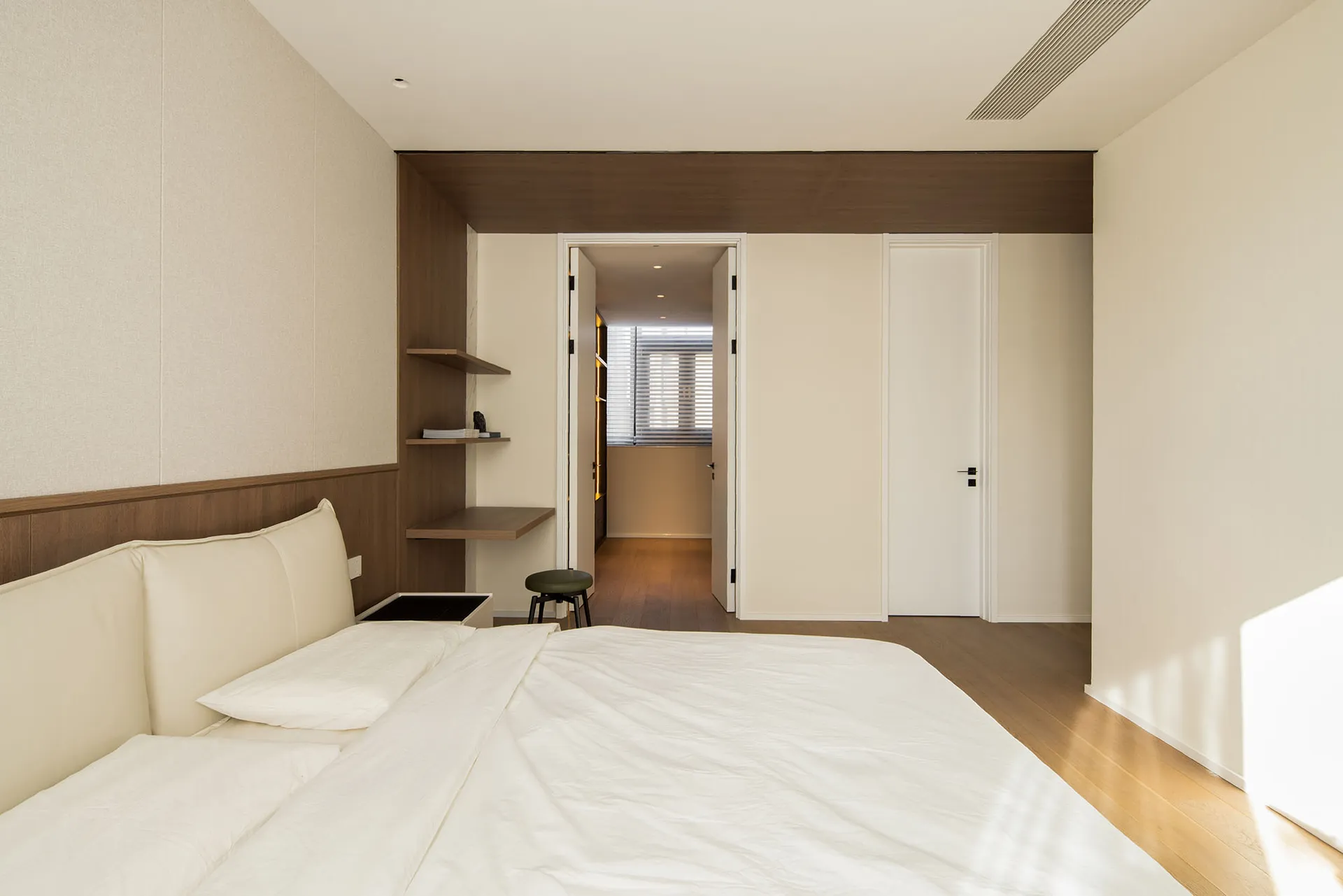 A minimalist bedroom with neutral-toned textiles and a modern design.