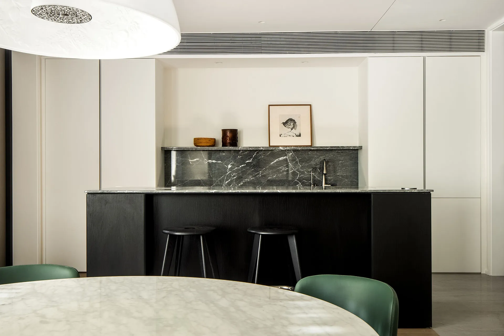 A minimalist kitchen interior with a marble countertop and black bar stools.