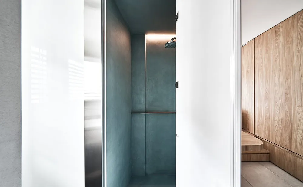 A minimalist bathroom with gray concrete walls and a chrome shower head.