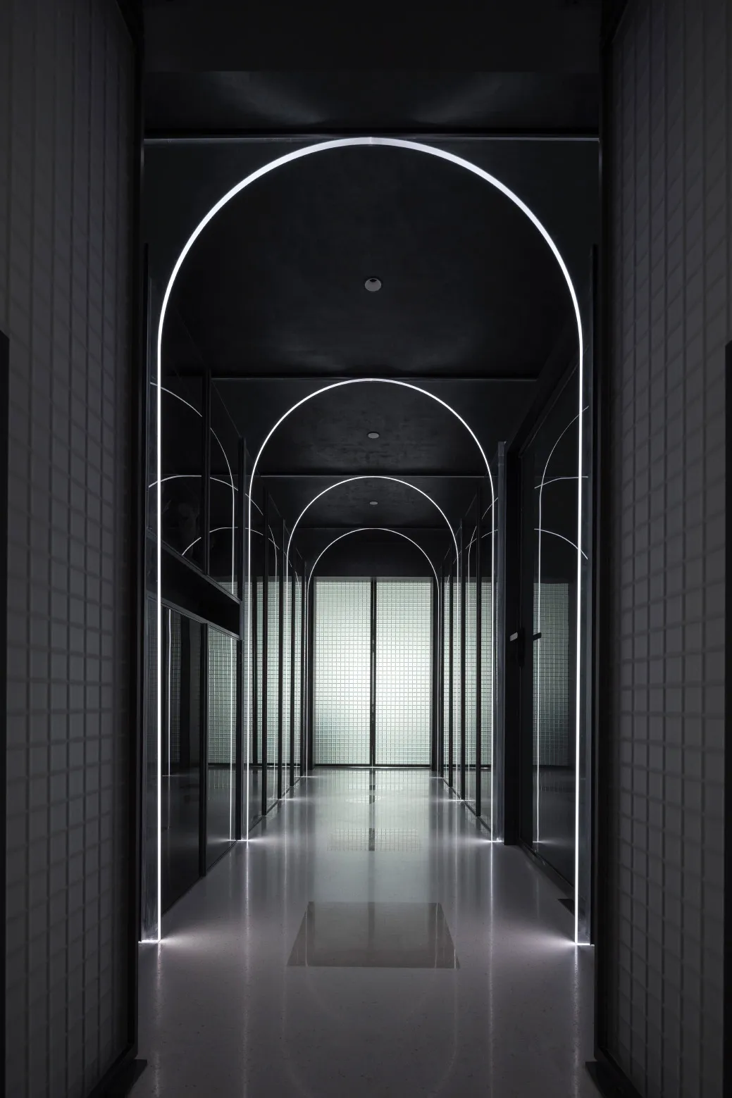 A modern interior corridor with glass walls and recessed lighting.