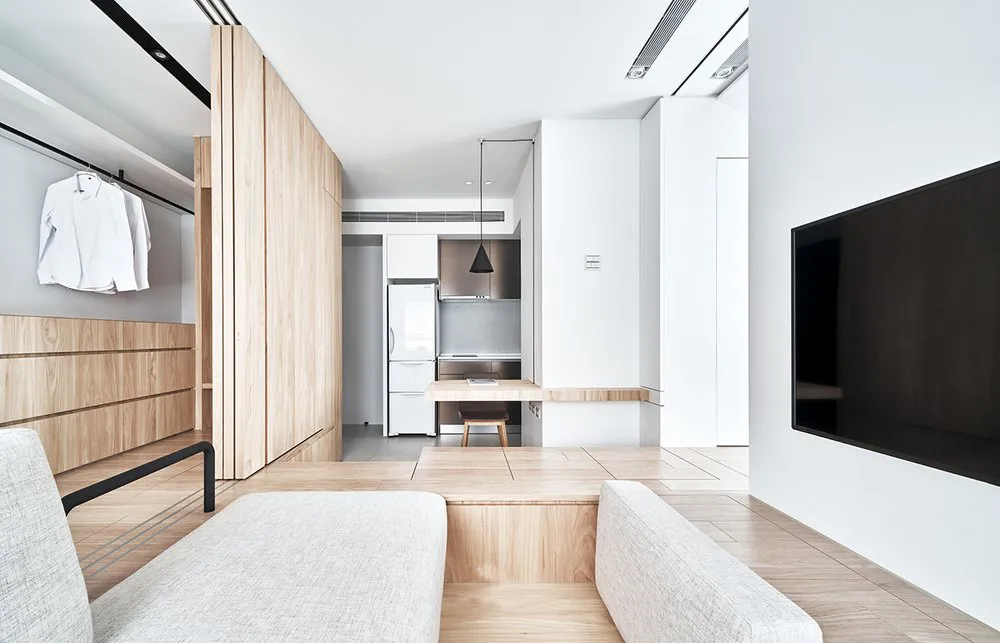 Modern minimalist apartment featuring a white wood floor, white walls, and white minimalist furniture, with a white refrigera