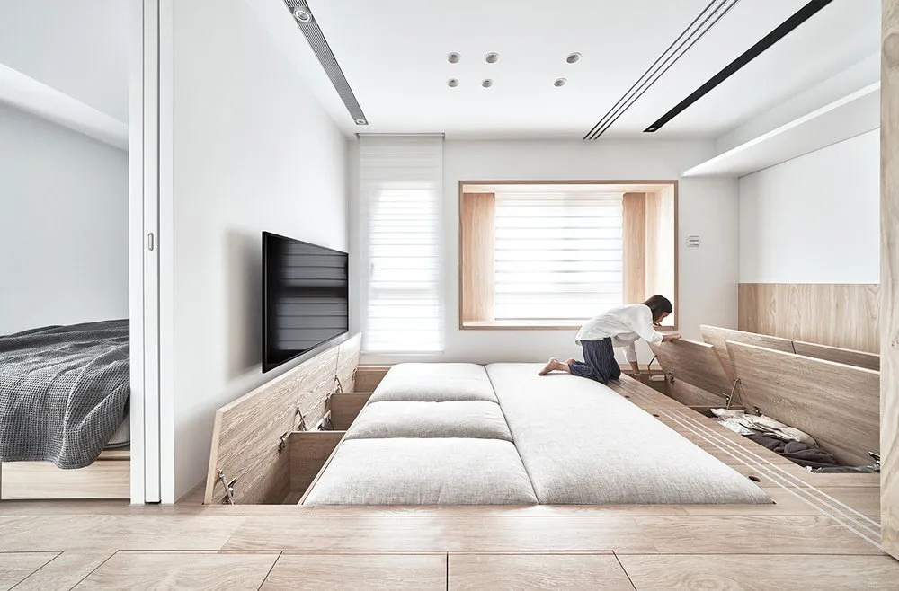 A modern minimalist bedroom with storage beds, a large window, and a TV.