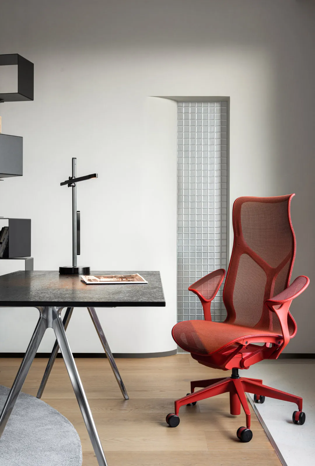 Modern office setup featuring a red ergonomic chair with metallic frame and a rectangular metallic table.