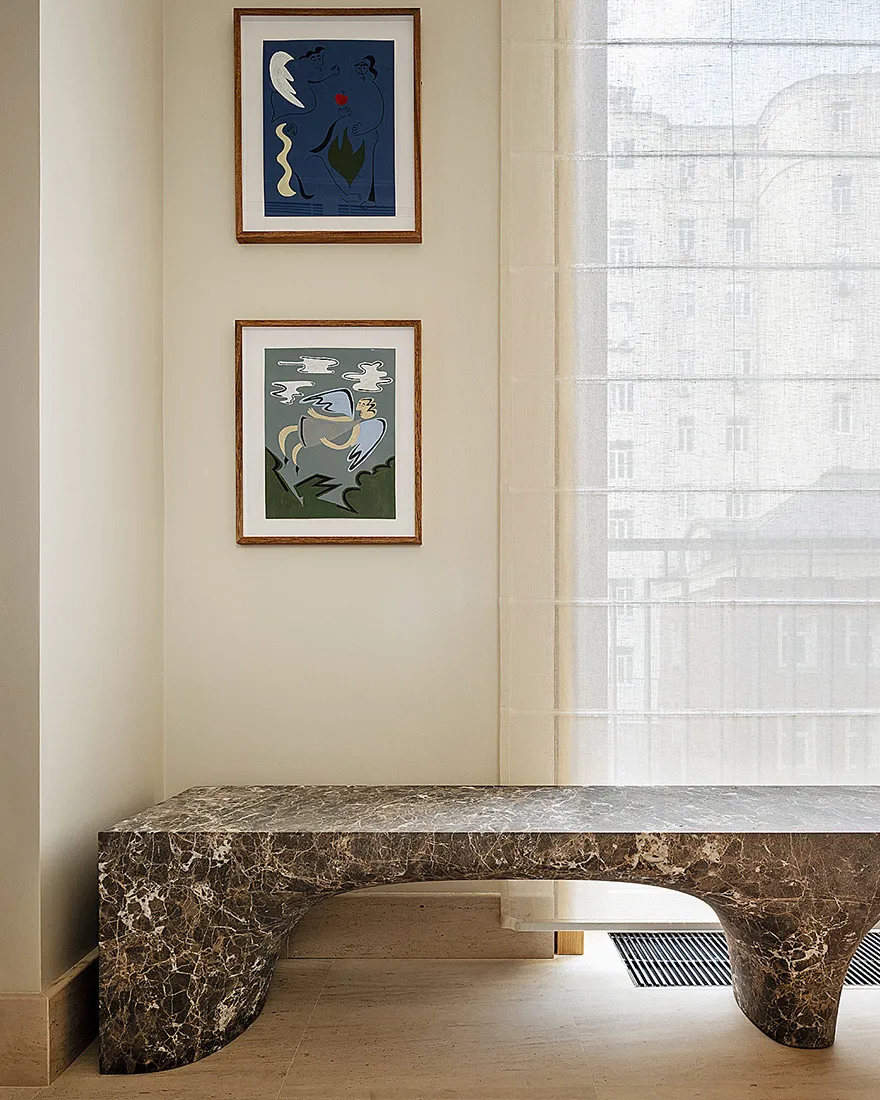 A modern interior space featuring a curved marble bench and two framed artworks on the wall.