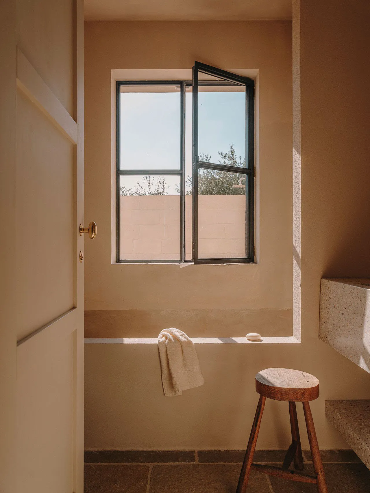 Minimalist bathroom featuring concrete walls and floor with an open window.