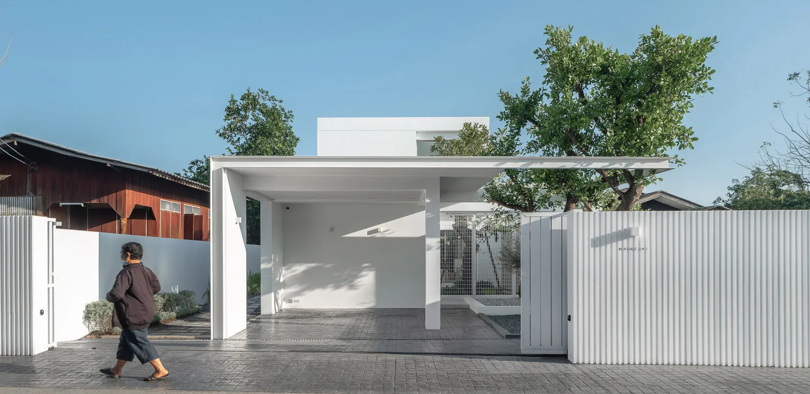 A minimalist house with a white exterior, featuring concrete and metal materials.