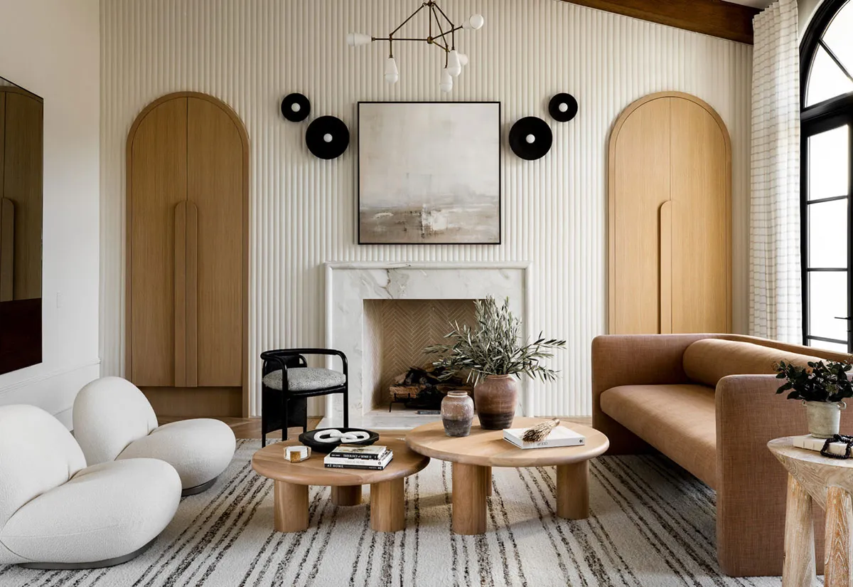 A minimalist living room featuring a marble fireplace, wooden tables, and a woolen rug.