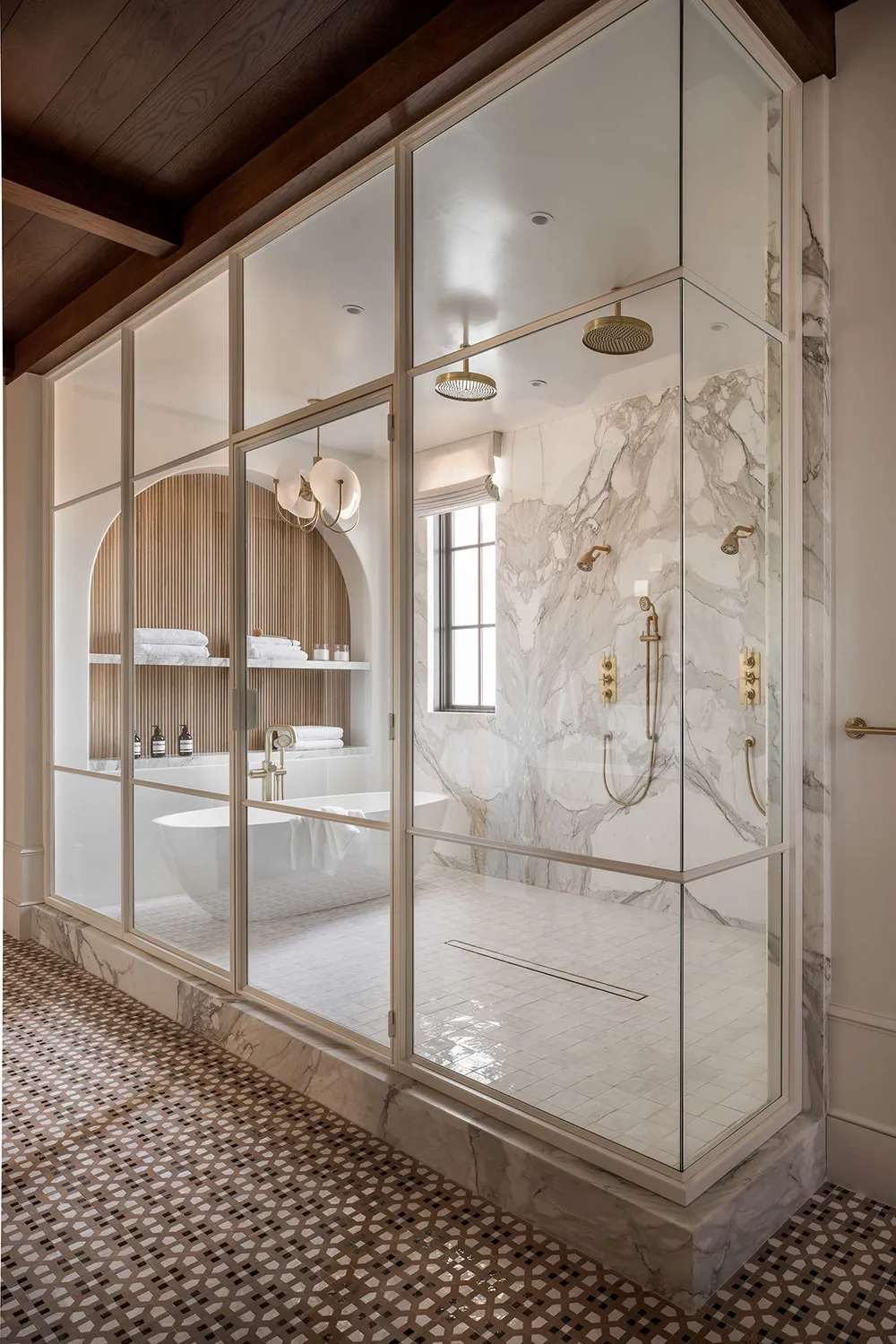 Modern, minimalist bathroom with marble walls and floor, glass shower enclosure, and freestanding bathtub.