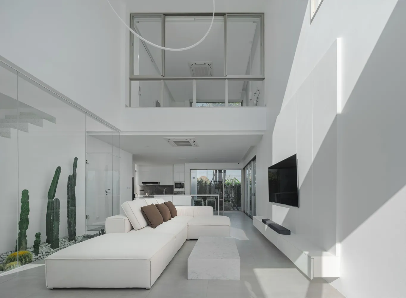 A minimalist living room with white concrete walls, a white sectional sofa, and a concrete coffee table.