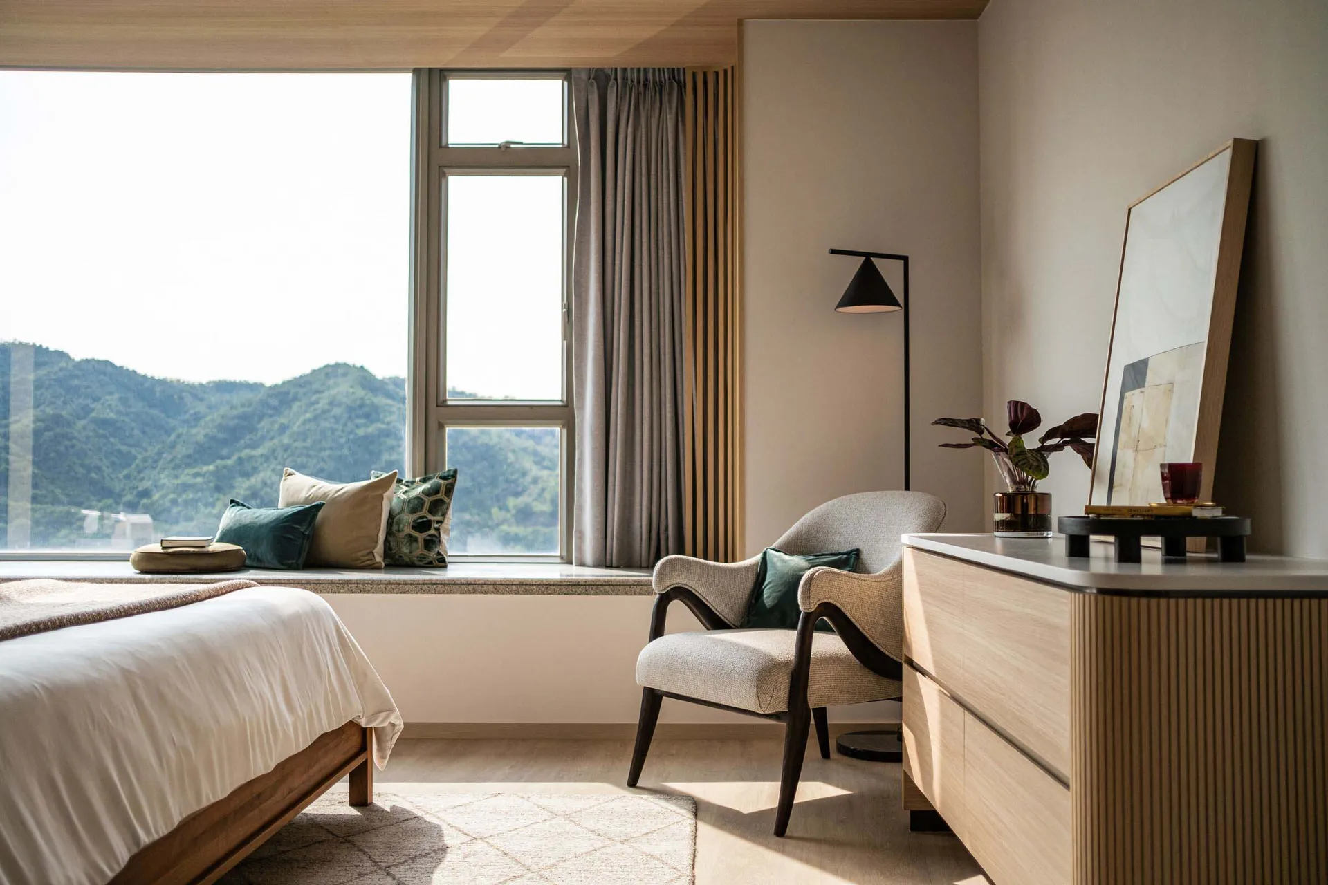 A modern minimalist bedroom featuring wooden furniture, fabric upholstery, and metallic accents.