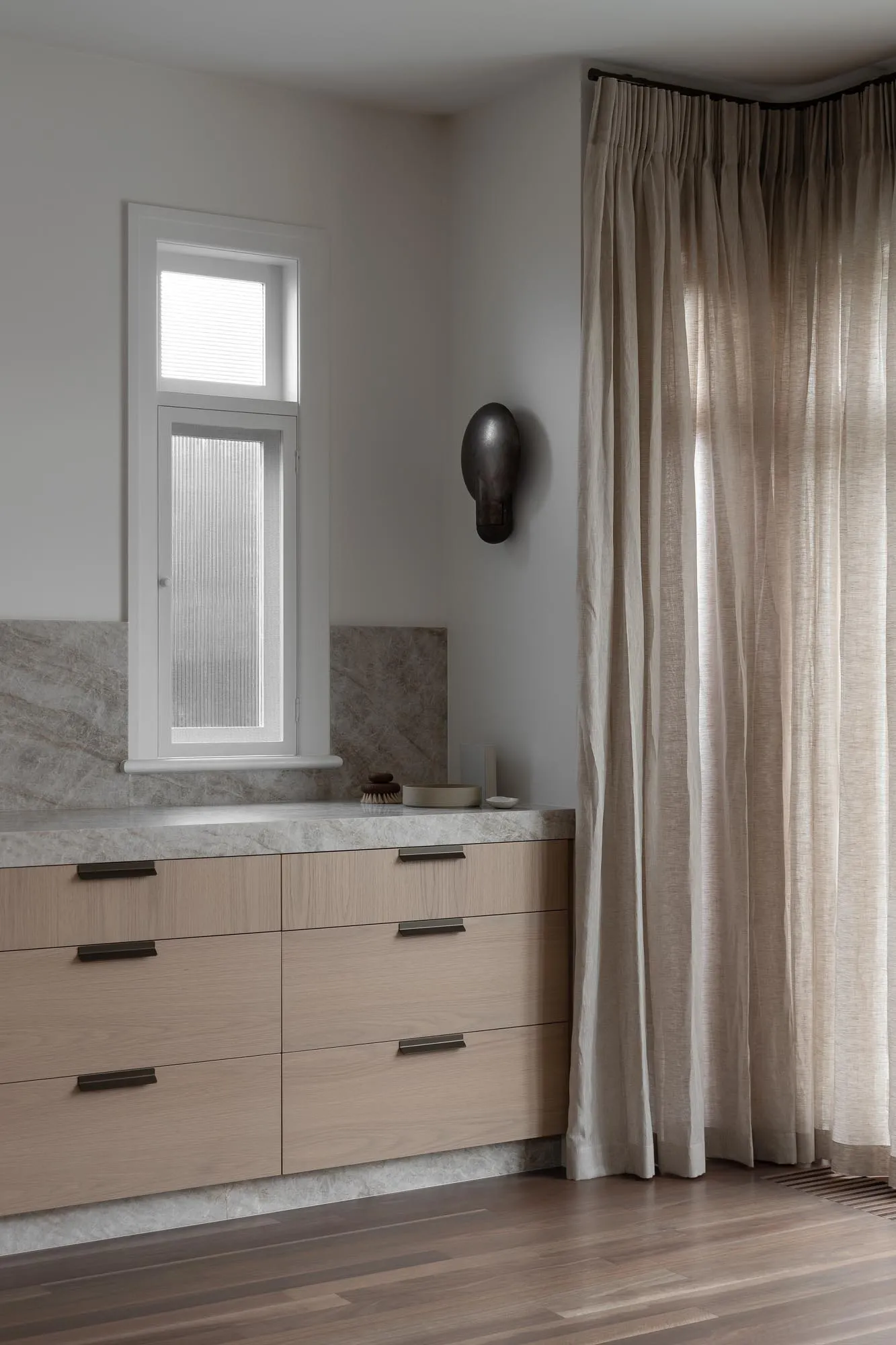 Modern bathroom featuring storage space with marble surface and concrete accents.