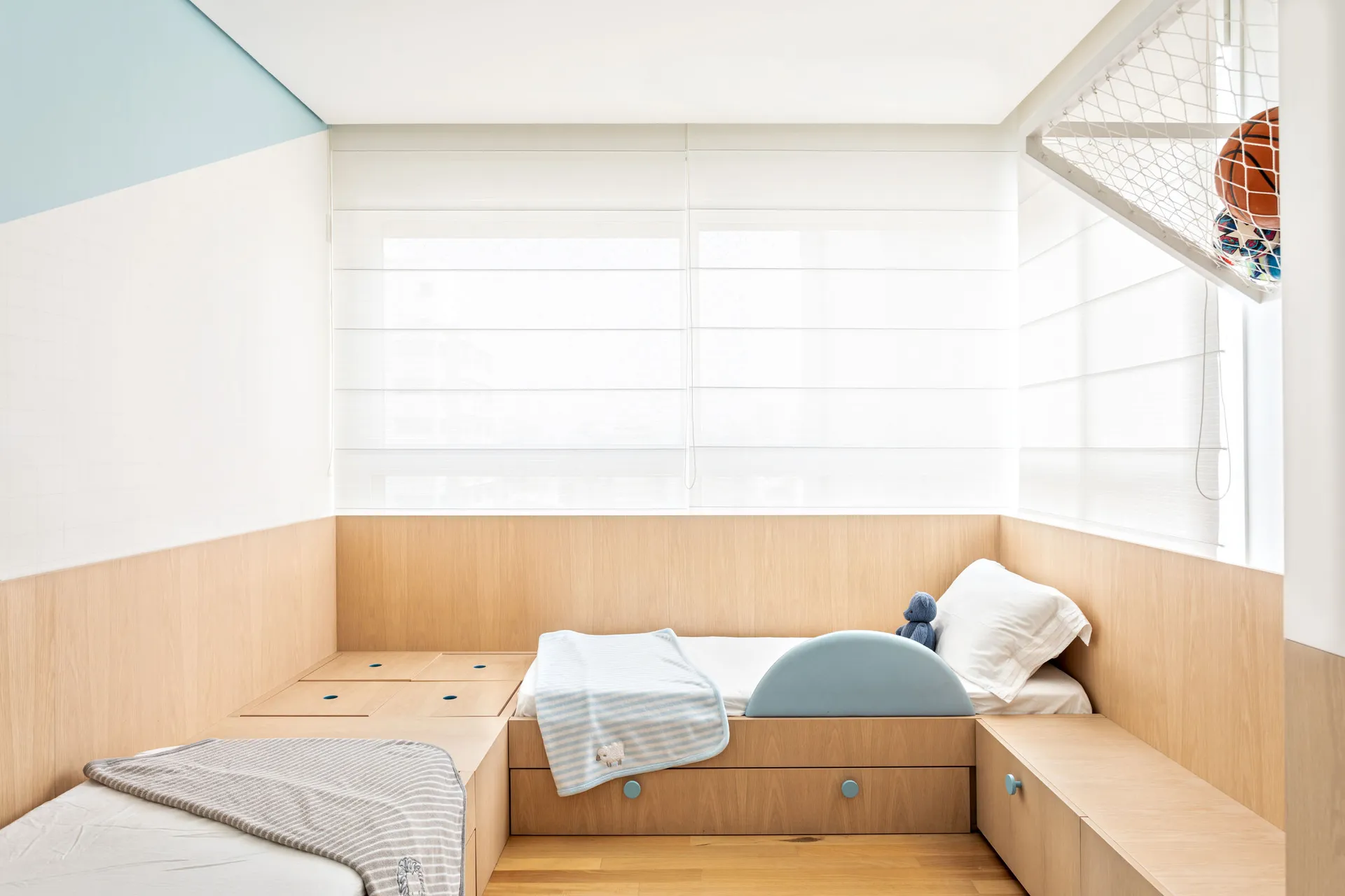 Minimalist bedroom featuring wood furniture and a bed with a blue blanket and pillow.