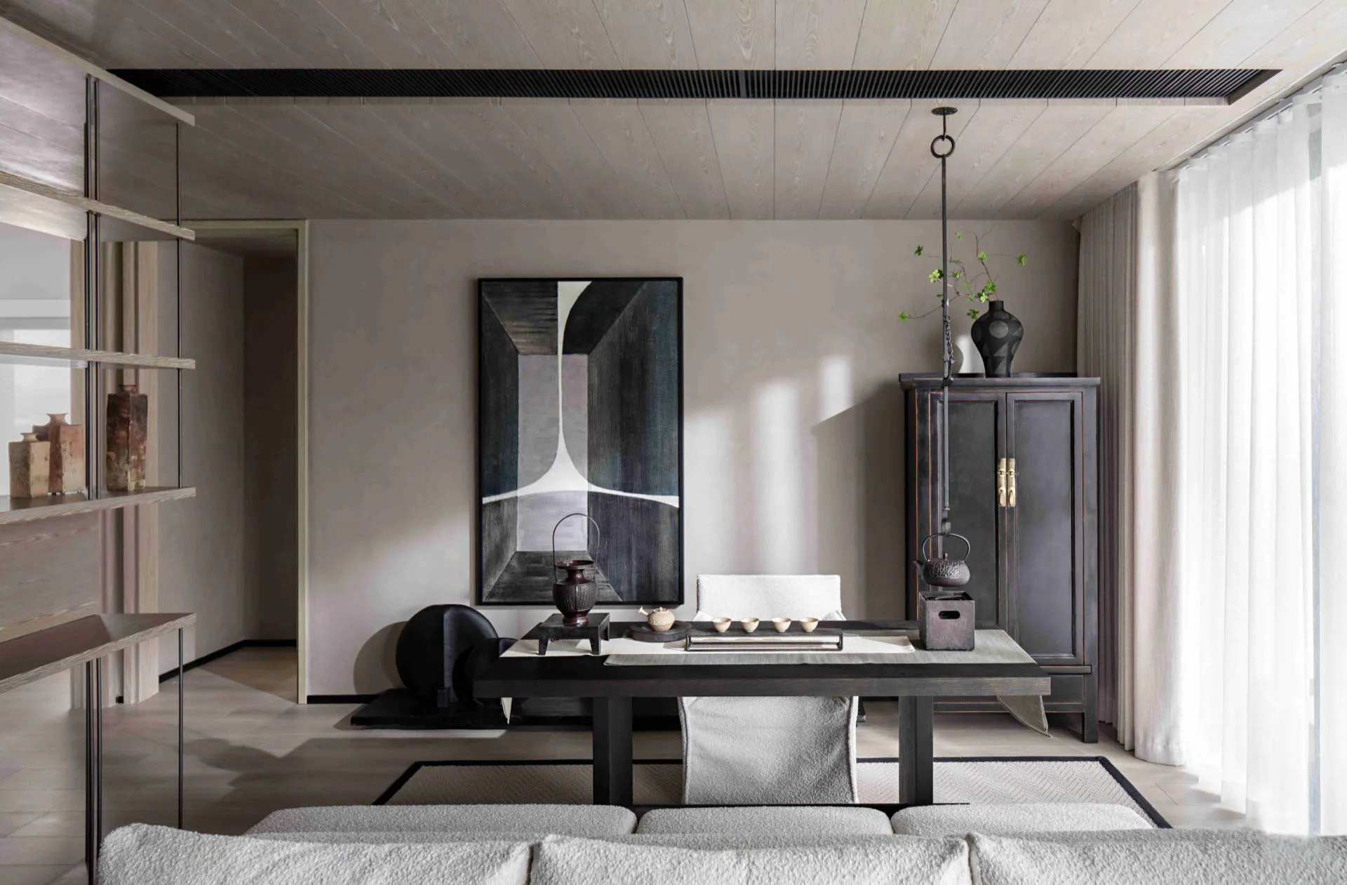 A minimalist living room featuring a wooden dining table and floor, a light-colored sofa, and a geometric abstract painting h