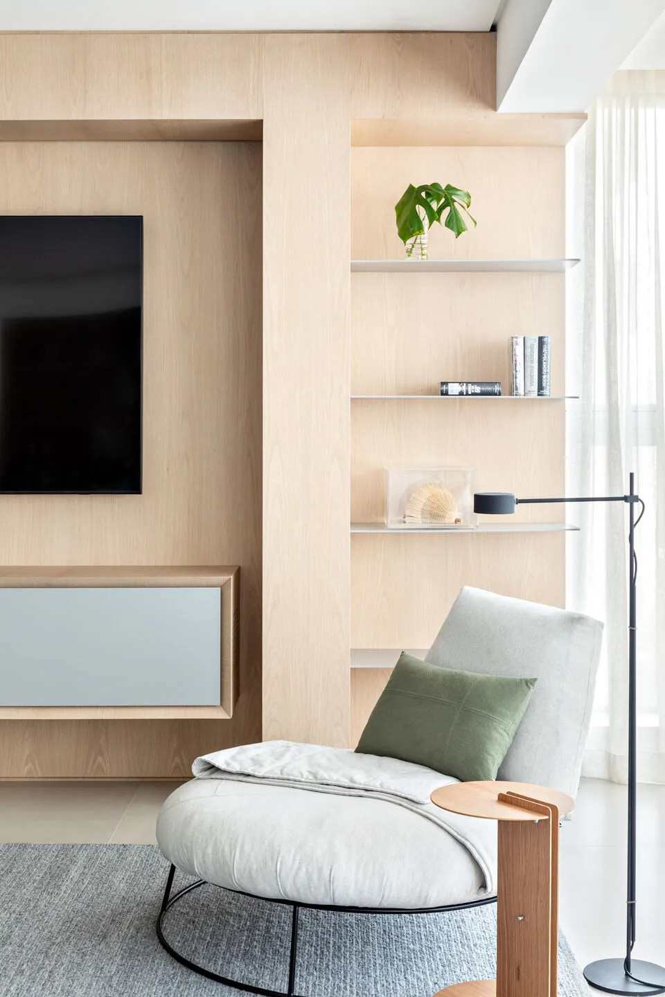 A minimalist living space with wooden walls, a comfortable upholstered chair, and a sleek entertainment unit.