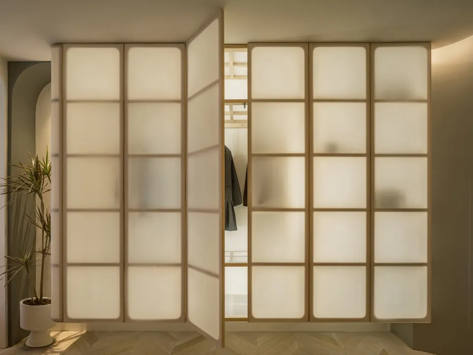 Modern interior design featuring a glass-paneled wardrobe with brown wooden accents.