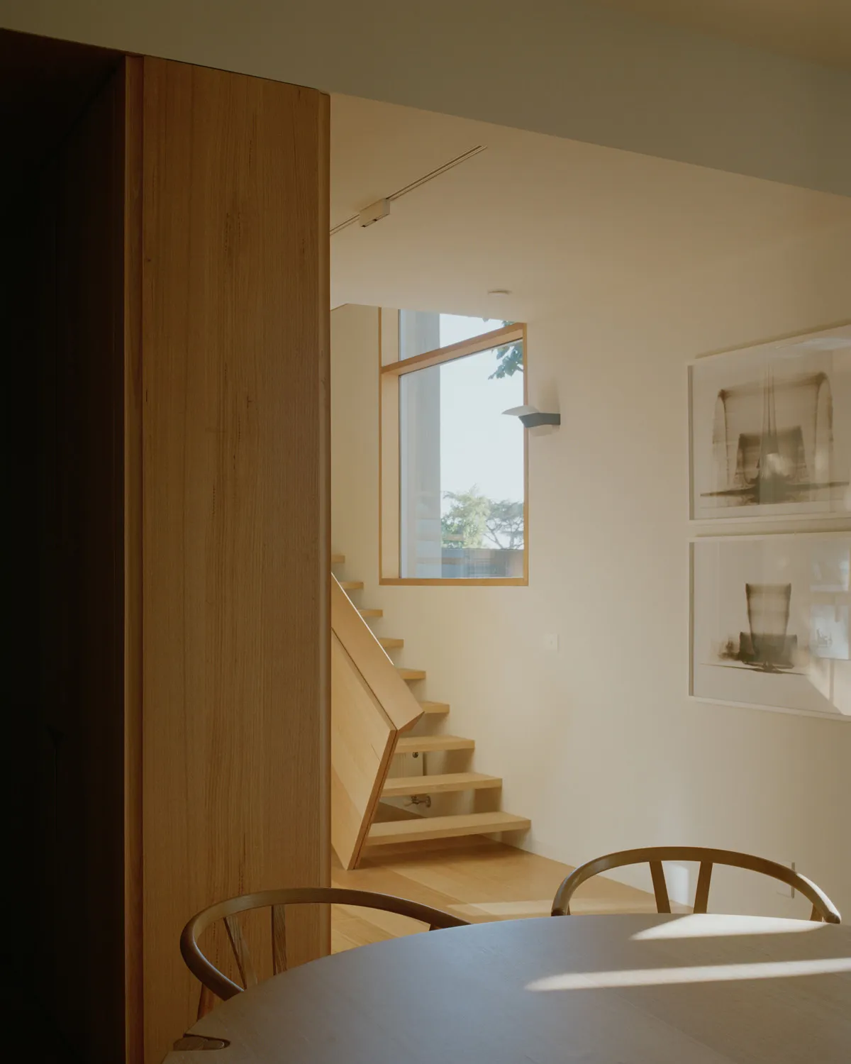 Modern interior with wooden staircase, large window, and minimalist design
