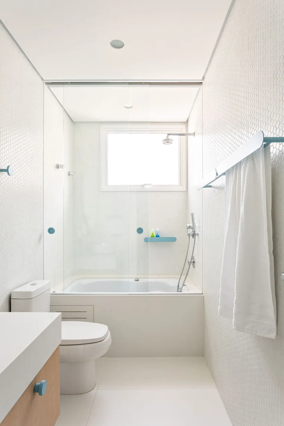 A modern minimalist bathroom featuring white tiles and glass elements.