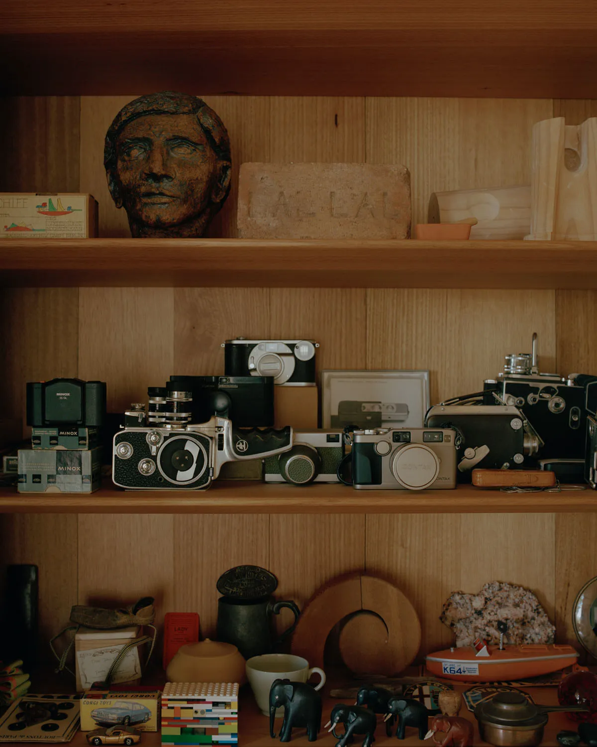 A wooden shelf adorned with vintage cameras, accessories, and decorative items.