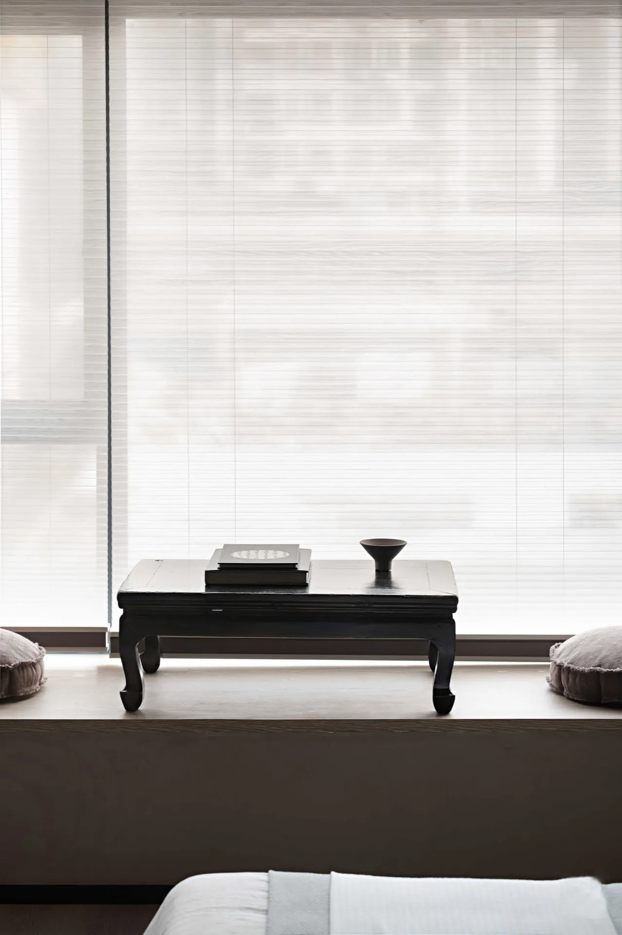 A minimalist residential interior features light wood, fabric, and glass materials.