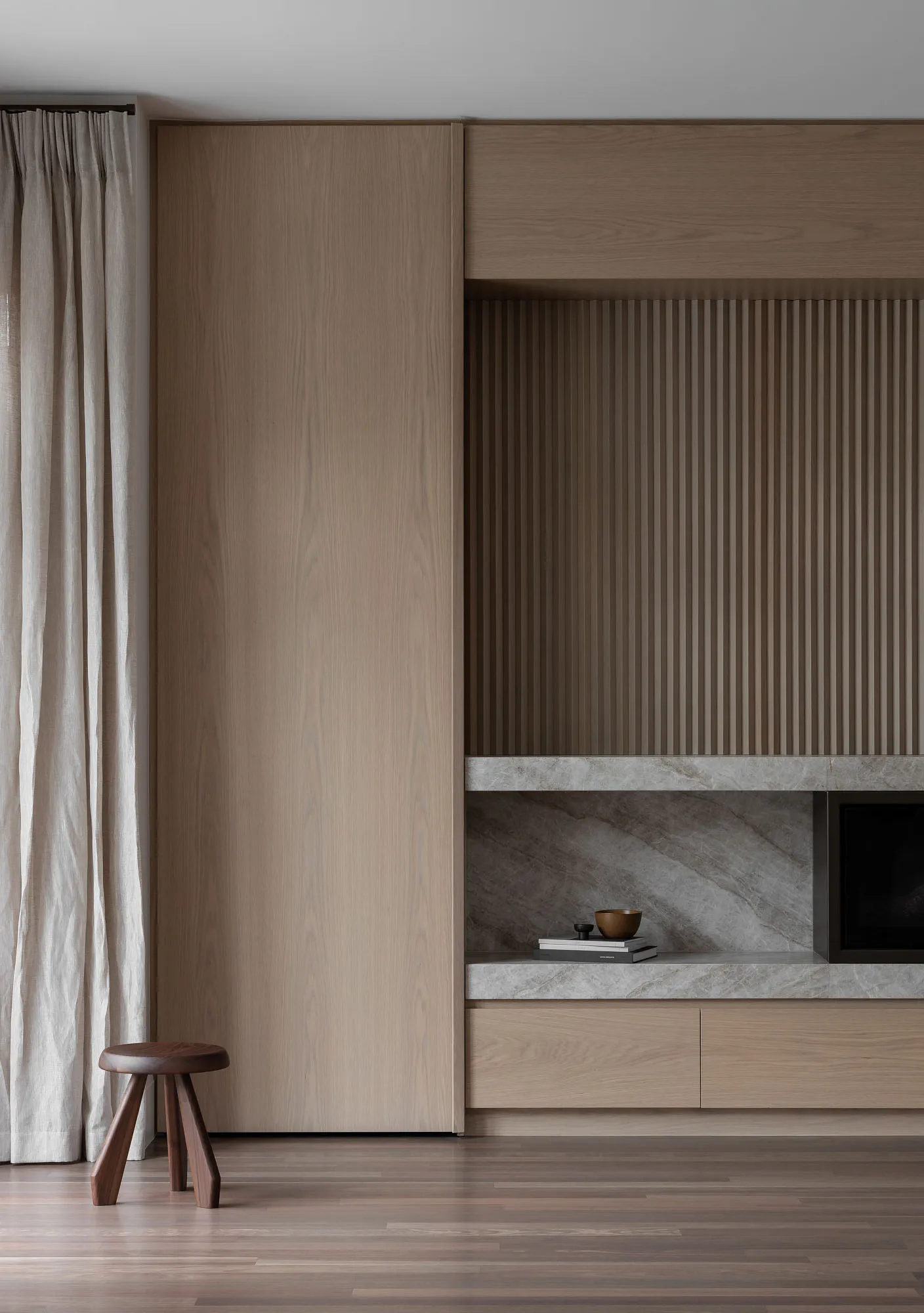 A minimalist living room featuring a modern wood cabinet and a window with curtains.
